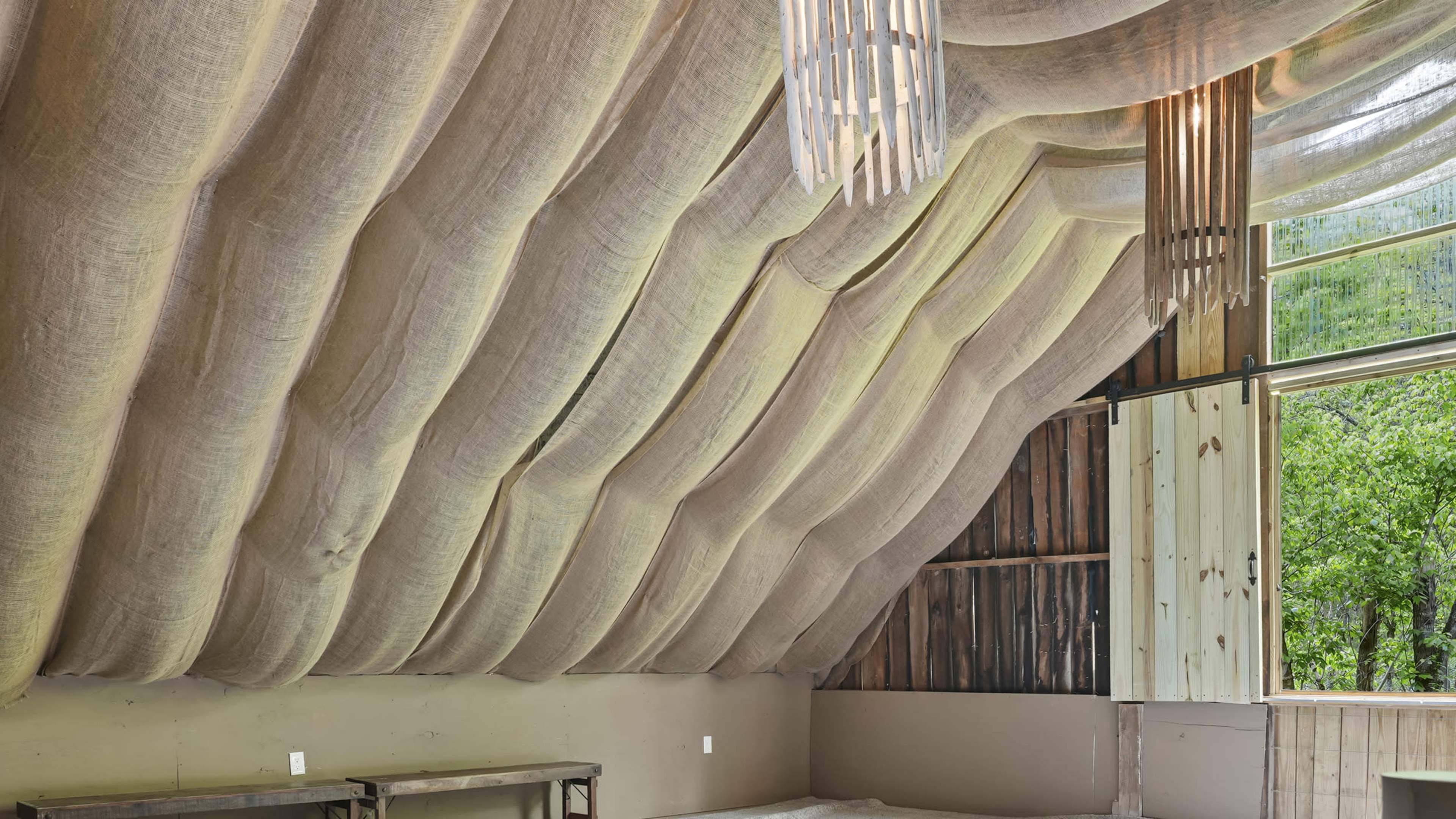 The interior features curved, textured walls with wooden accents and large windows overlooking greenery.