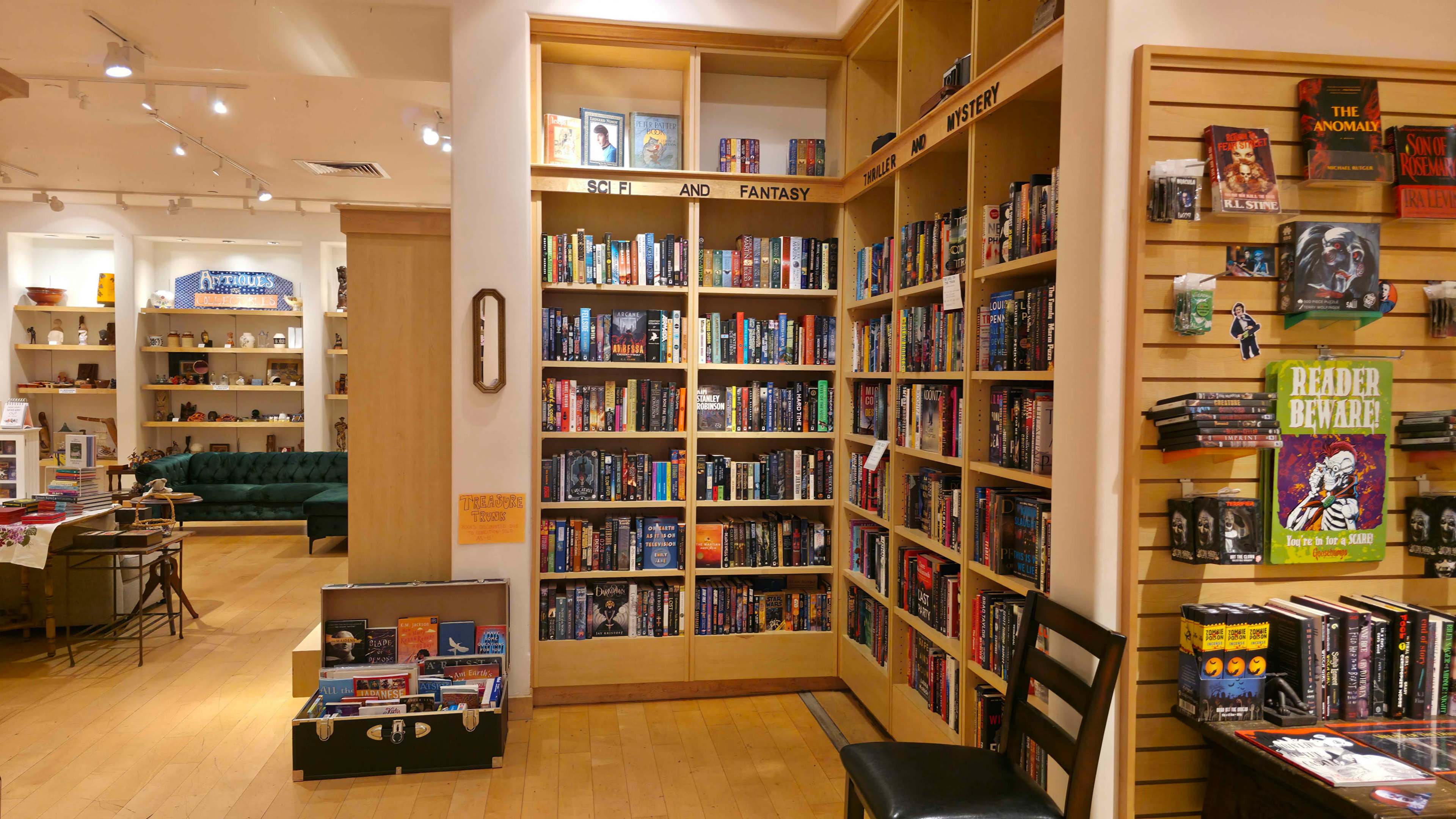 The image shows a bookstore interior featuring shelves filled with science fiction and fantasy books, alongside a display of various book titles and merchandise.