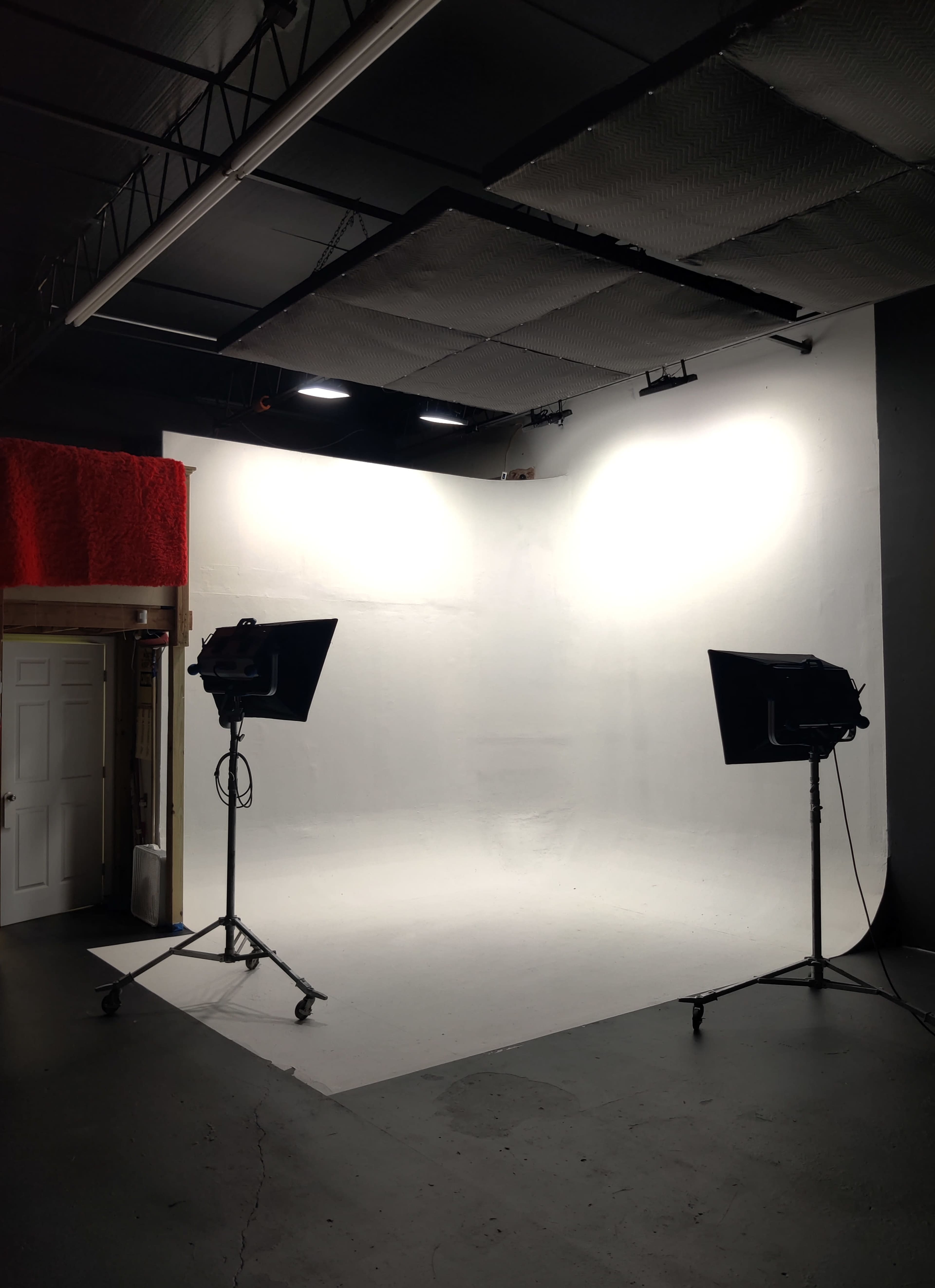 A photography studio with two lights on stands positioned in front of a white backdrop.