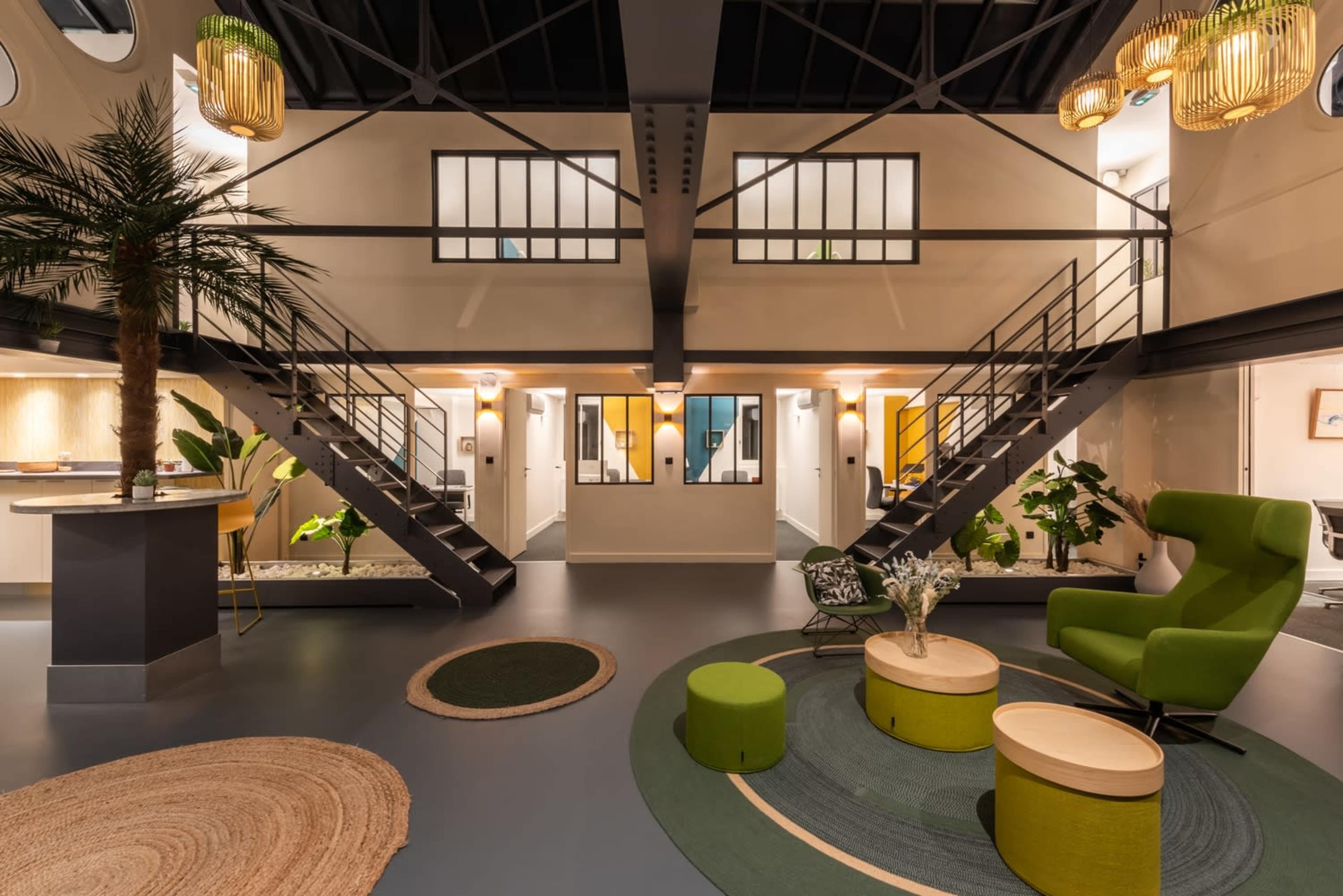 The image shows a modern interior space with a double staircase, green seating, and plants, designed in a minimalist style.