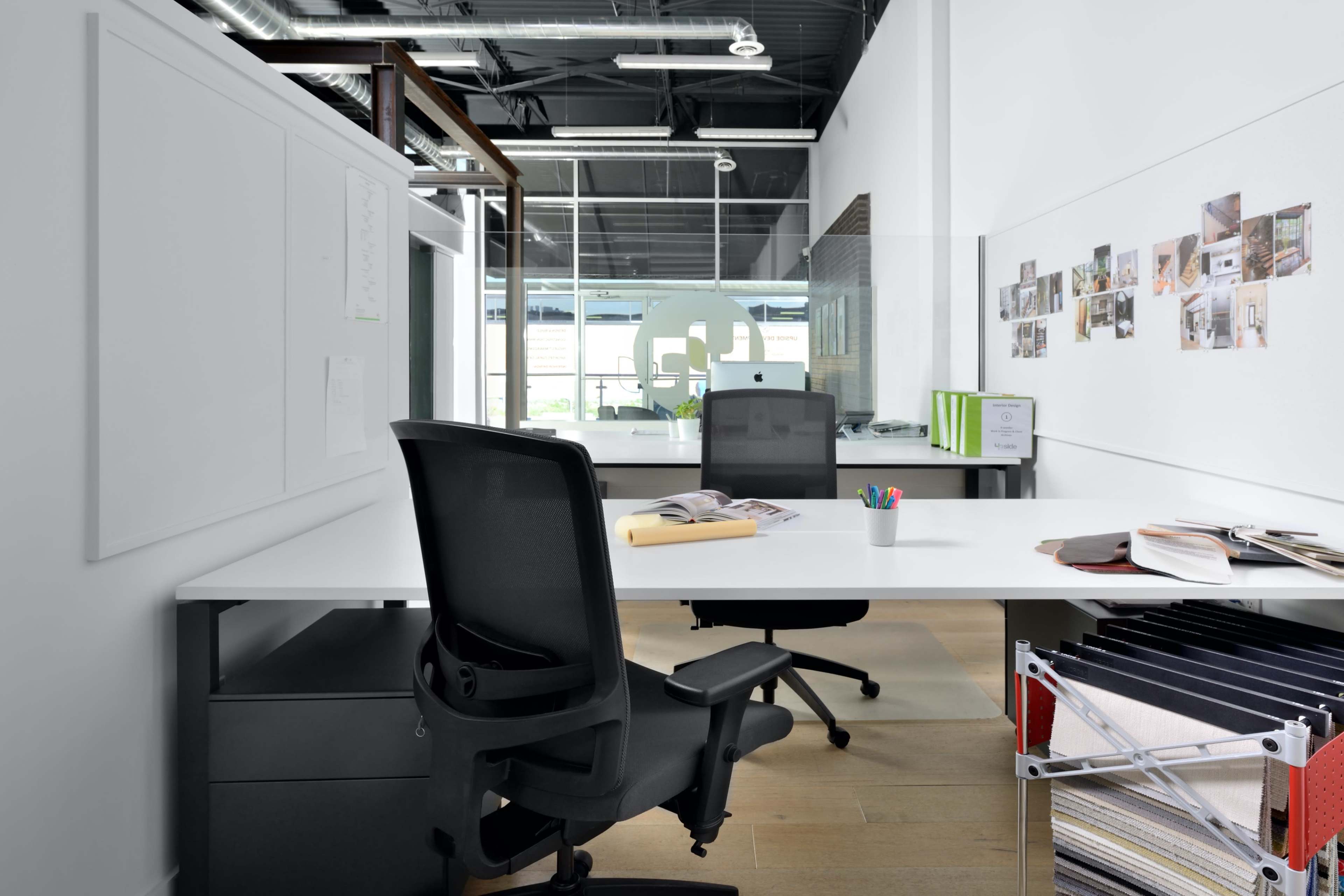 A modern office space featuring two desks with ergonomic chairs, a computer, and organized office supplies.