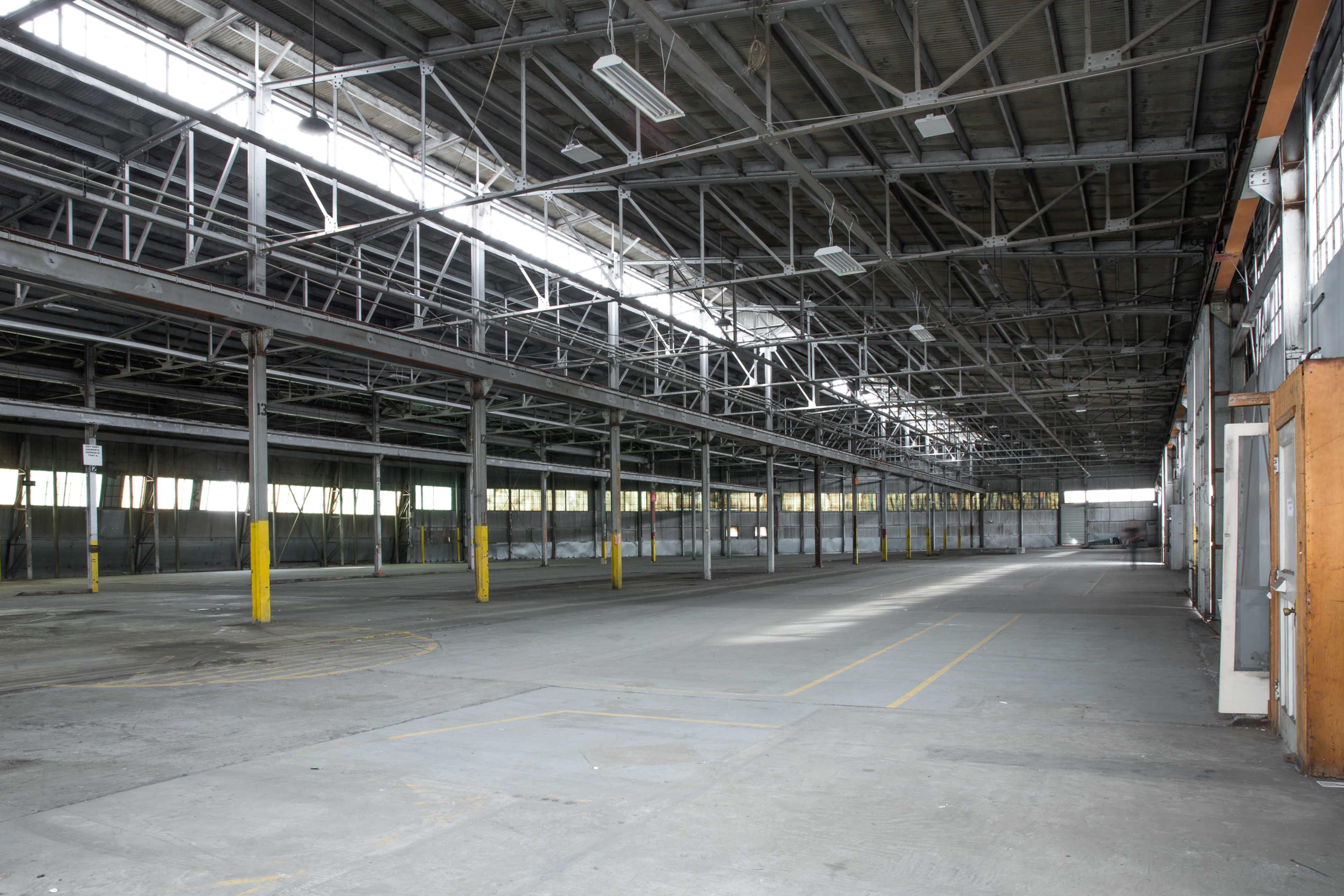 A large, empty industrial warehouse with high ceilings and a concrete floor.