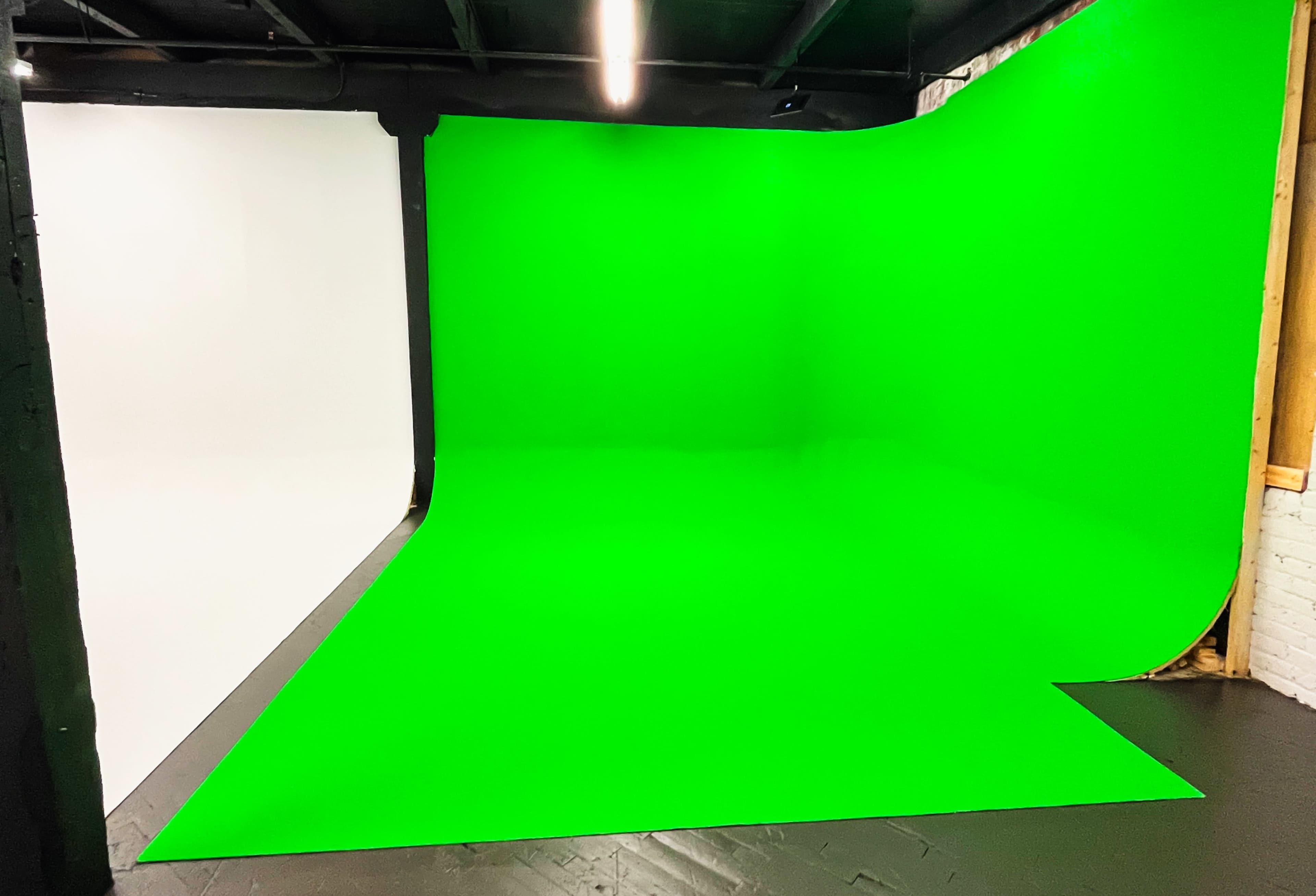 A photography studio featuring a green and a white backdrop with a seamless floor.