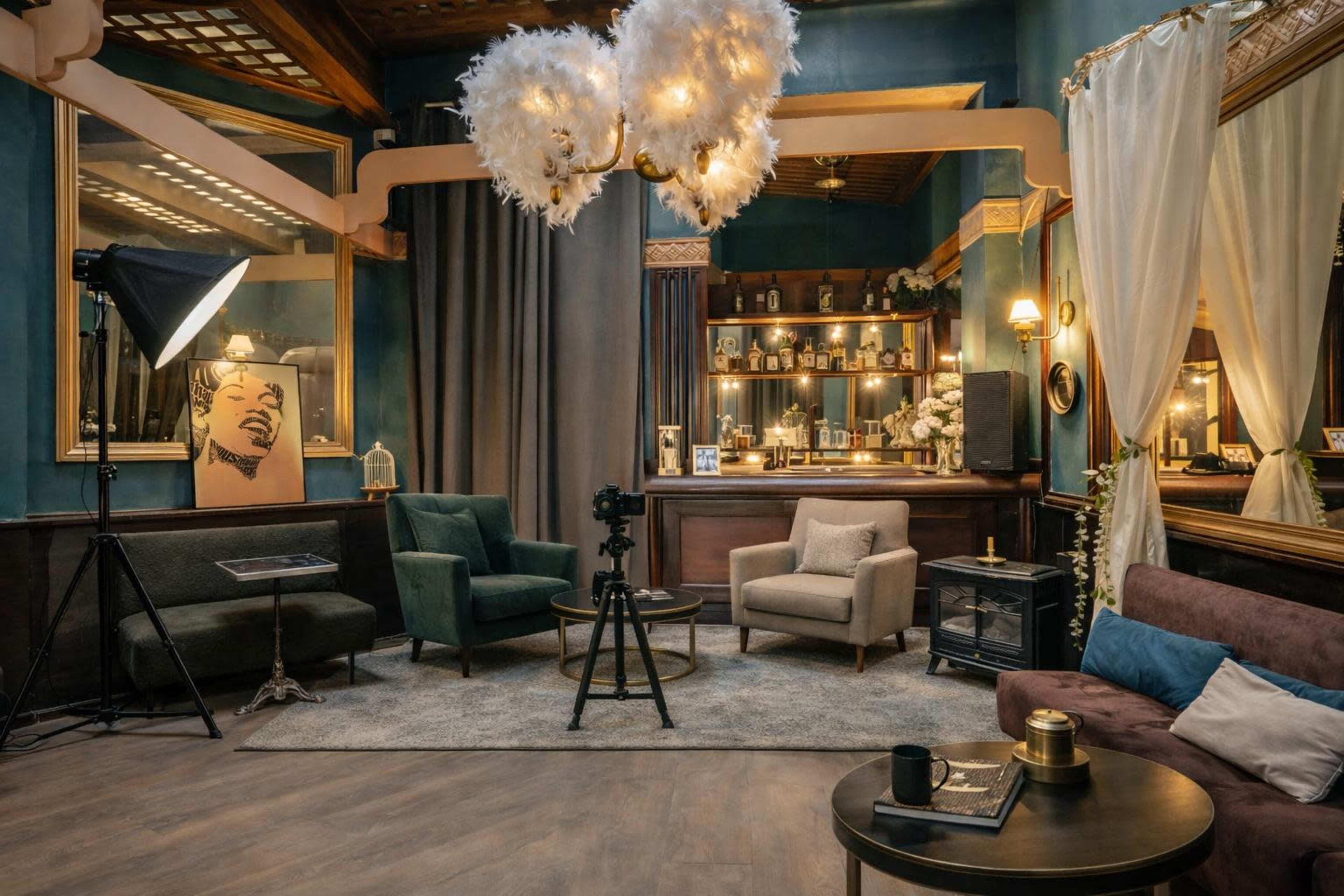 The image shows a stylish lounge area with various seating options, a large backdrop, and decorative elements like mirrors and artwork.