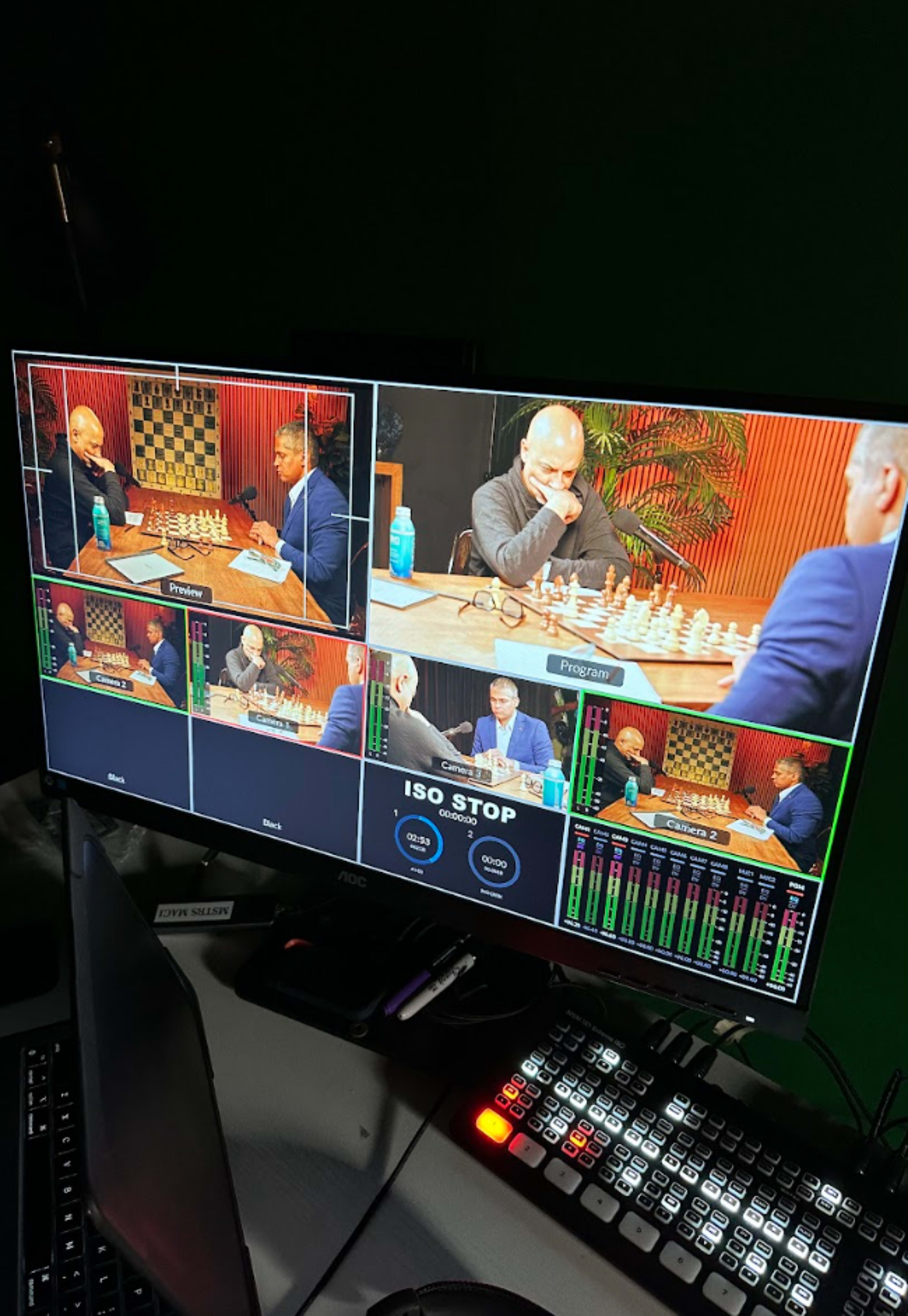 A computer monitor displaying multiple camera feeds of a chess match between two players.