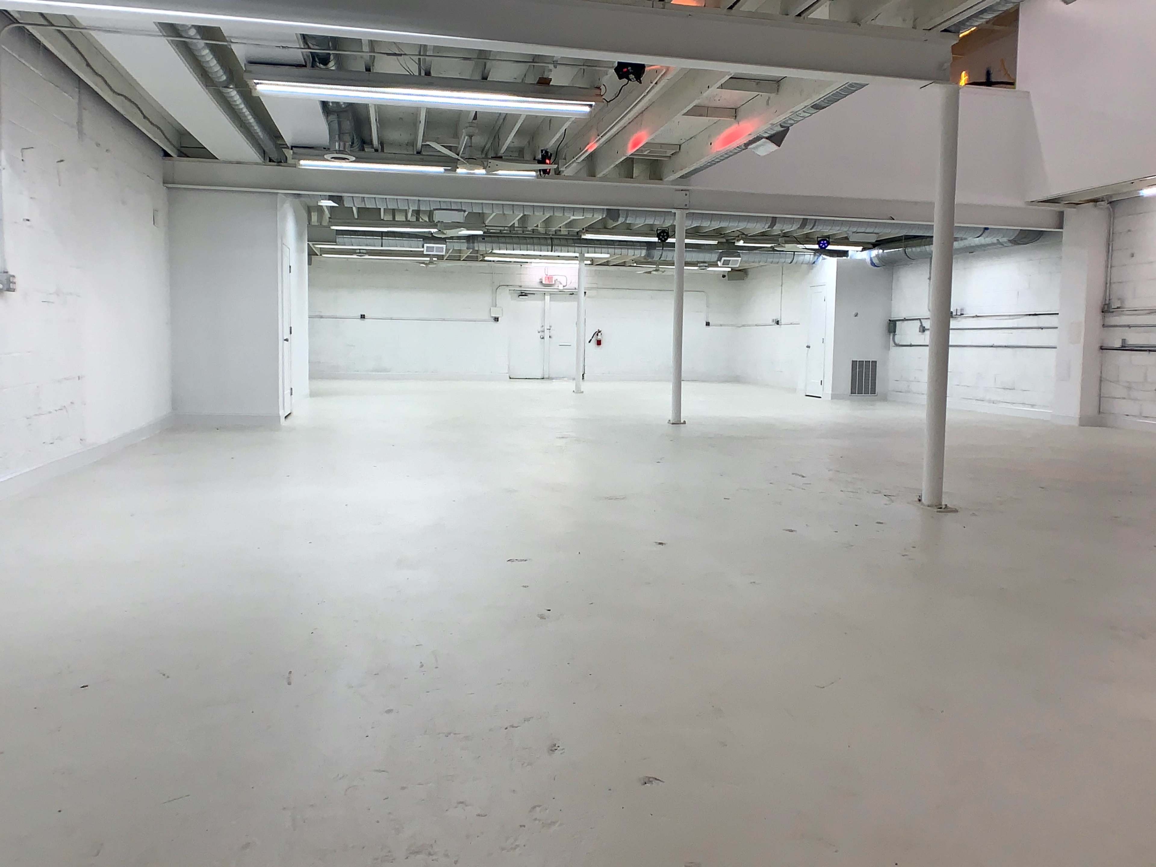 A large, empty industrial space with white walls and a smooth, light-colored floor.