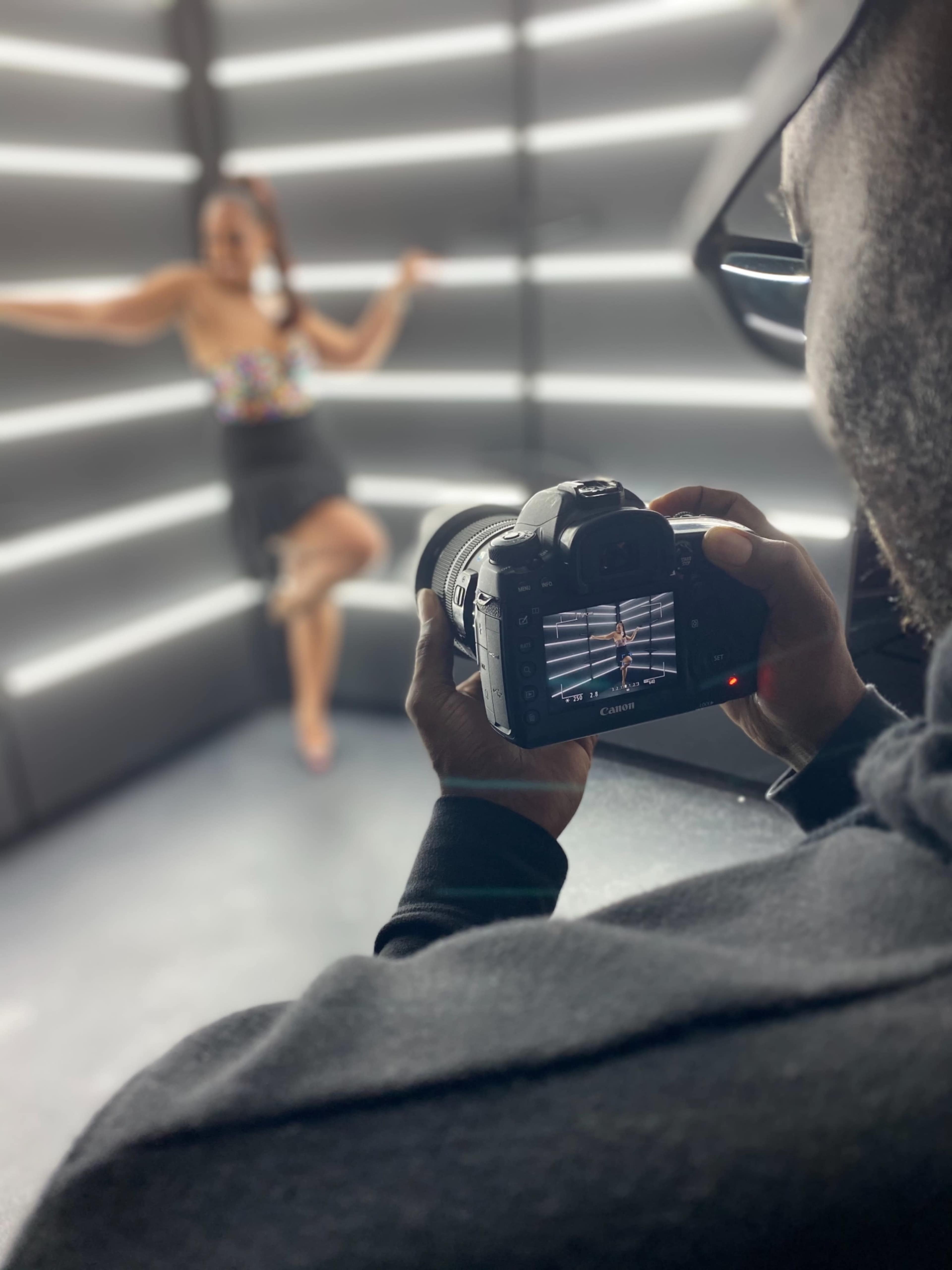 A photographer captures a model posing against illuminated vertical lines in a studio setting.