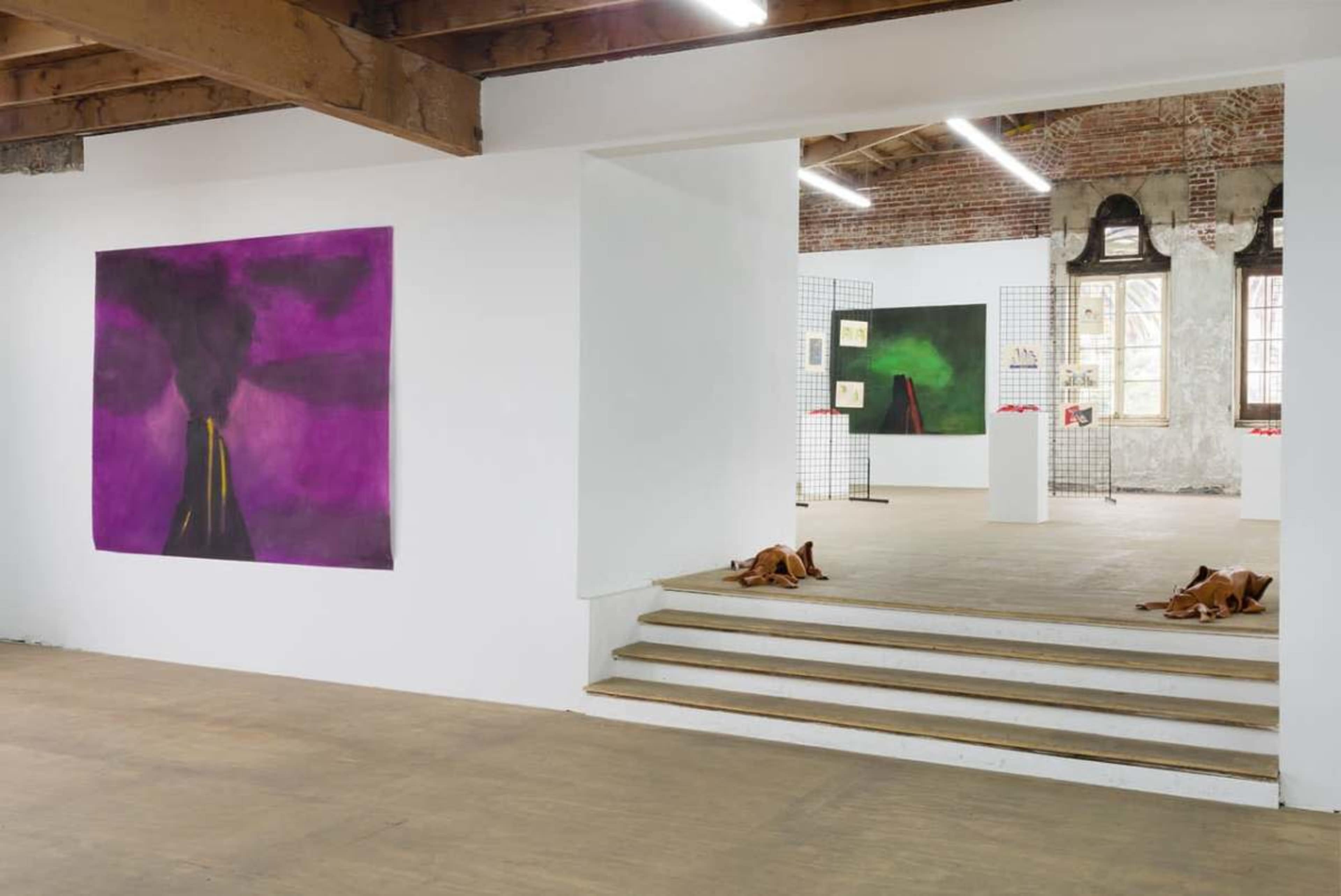An interior of an art gallery with large abstract paintings on white walls and steps leading to another exhibition space.