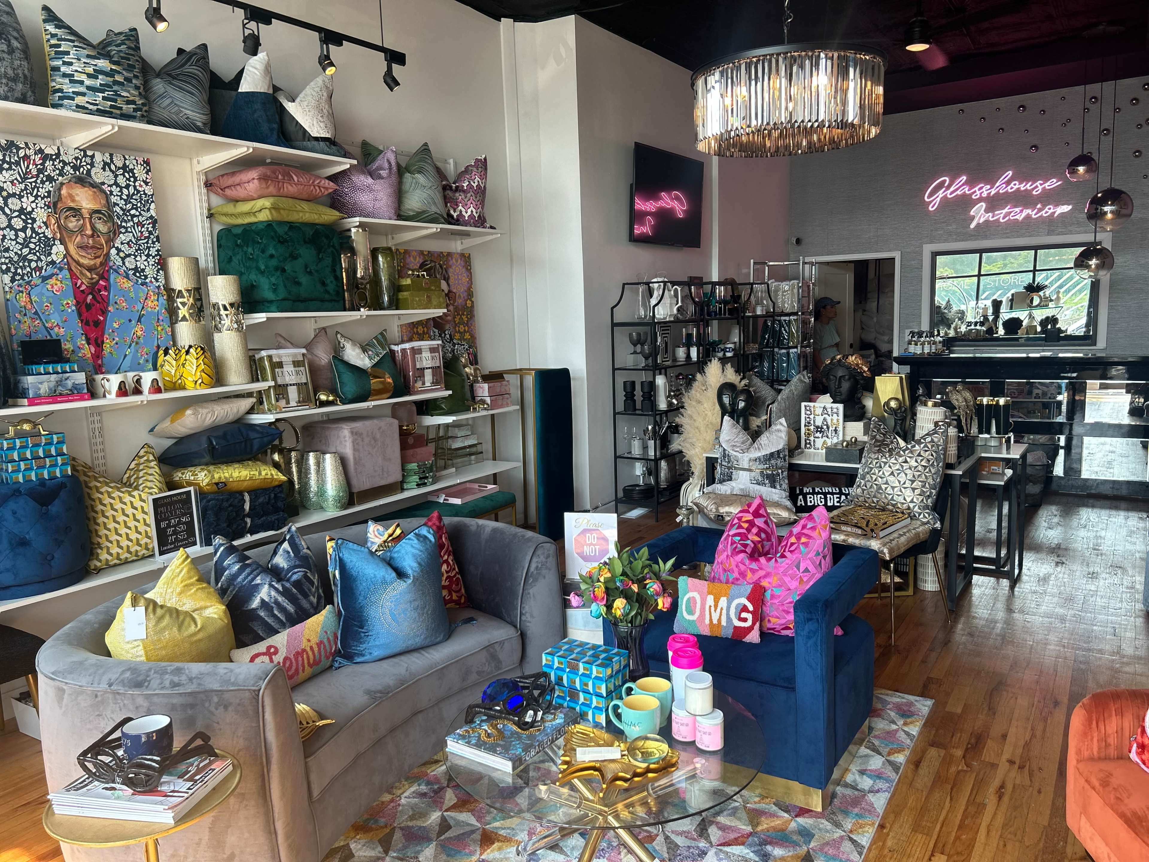 A vibrant interior home decor store displaying colorful throw pillows, artwork, and decorative items on shelves and tables.