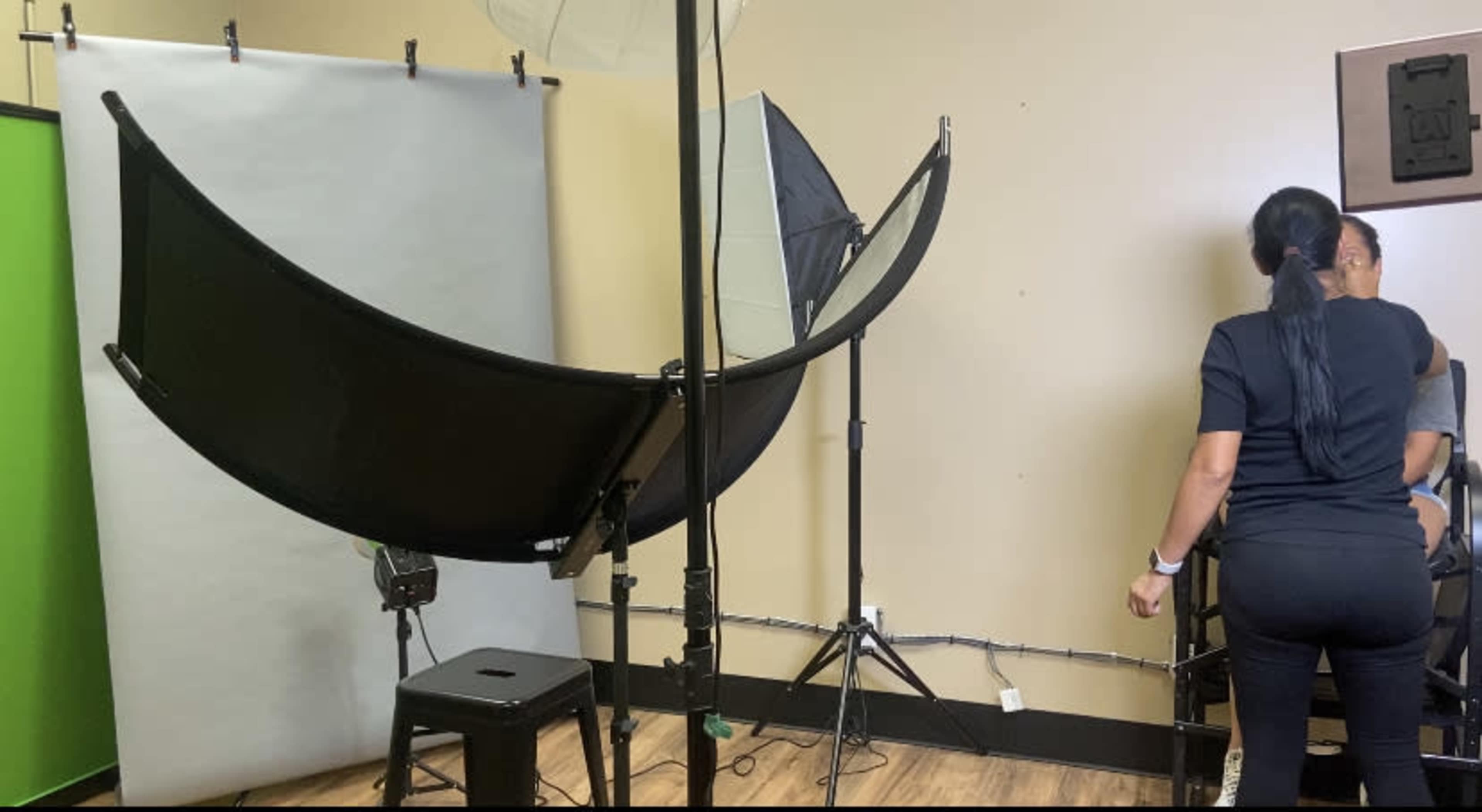 A photography studio setup features a backdrop, lighting equipment, and a person preparing for a photo shoot.