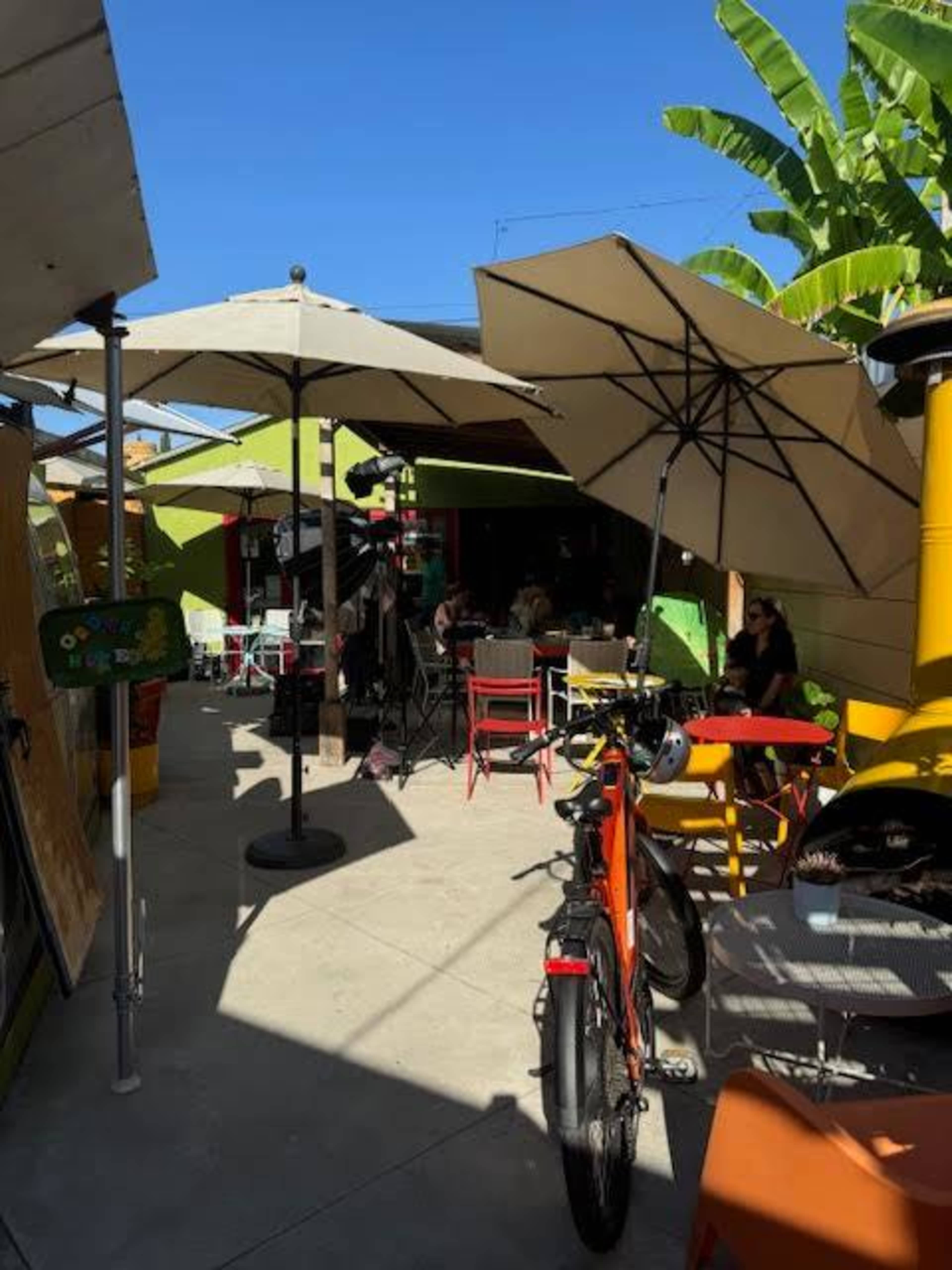A vibrant outdoor seating area at a café features patio umbrellas, colorful chairs, and a bicycle parked nearby.