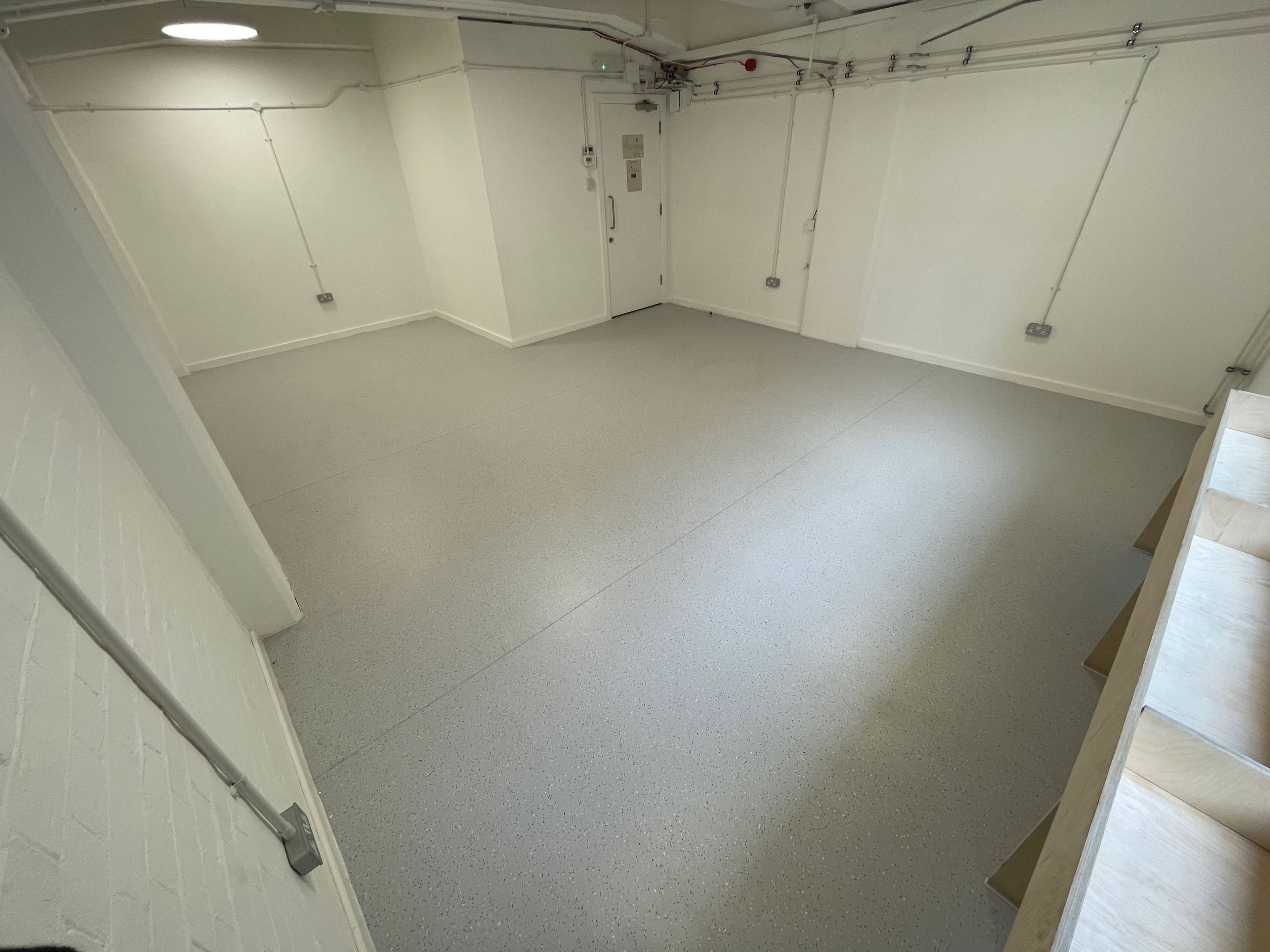 An empty room with gray flooring, white walls, and a door on one side.