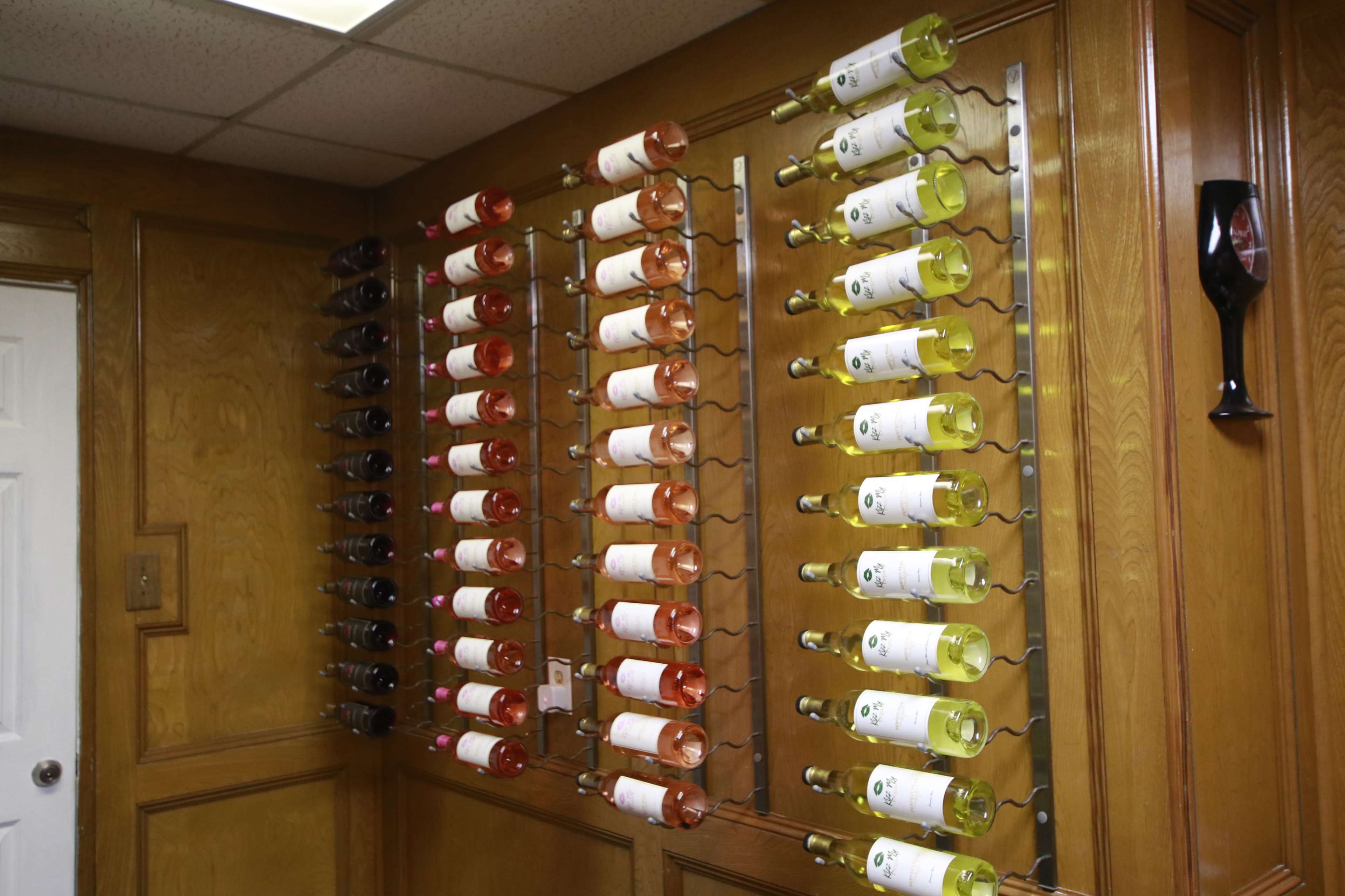 A wall-mounted wine rack displaying various bottles of wine organized by color.