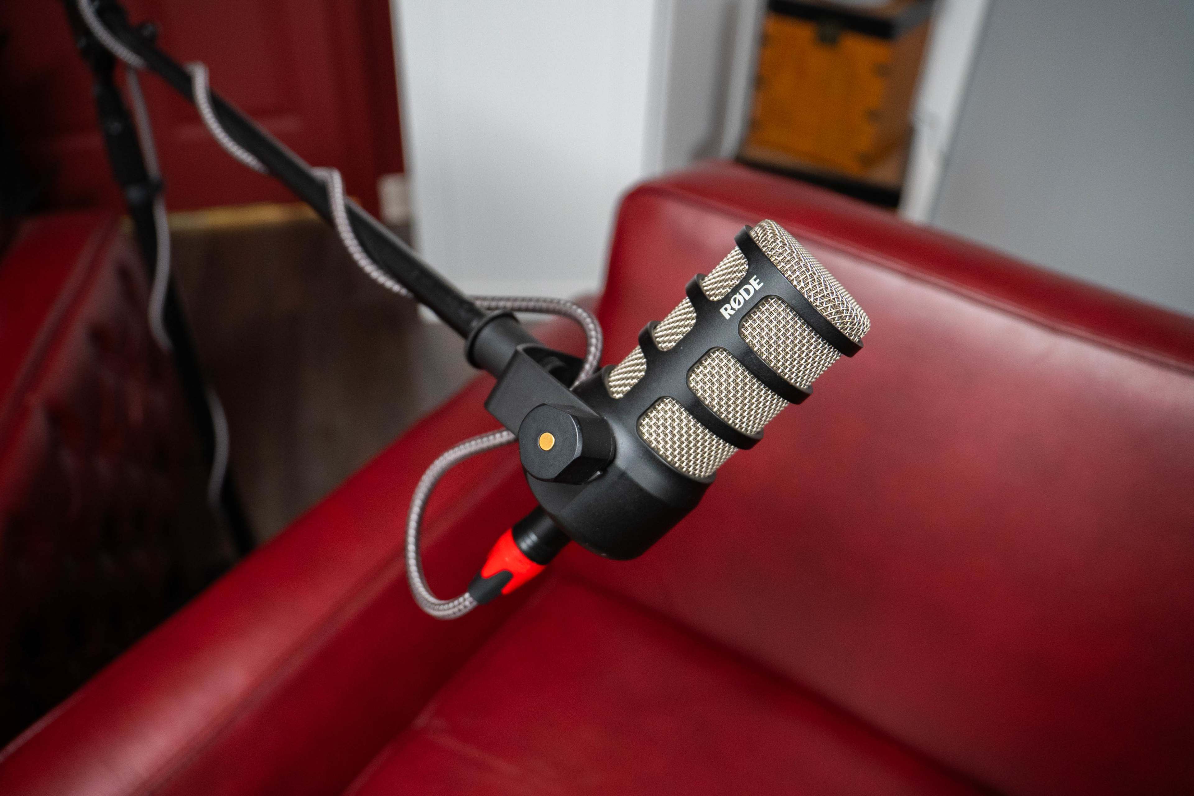 A microphone is positioned on a stand next to a red leather chair.