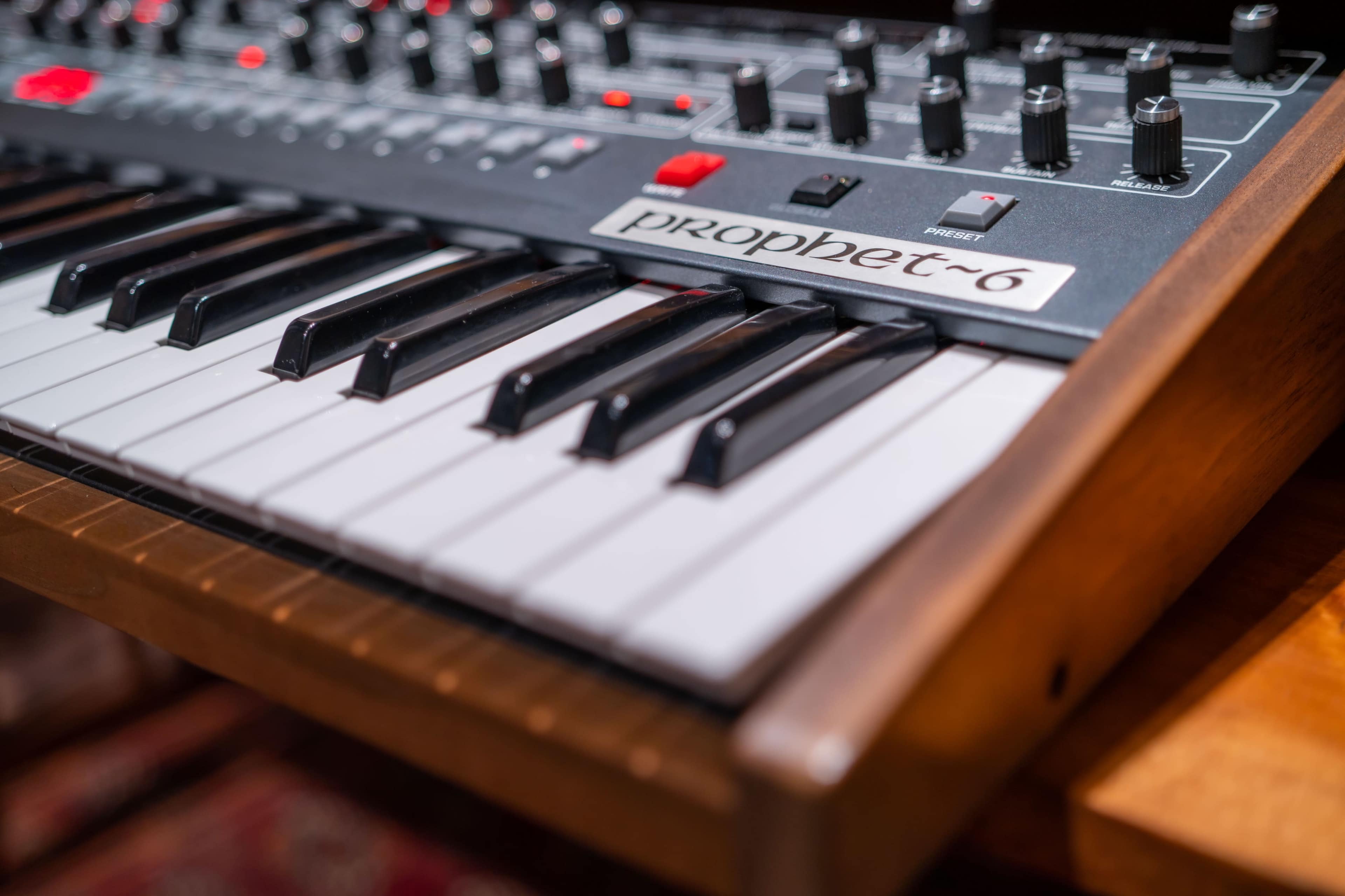 A close-up of a Prophet-6 synthesizer with its keyboard and control panel prominently displayed.