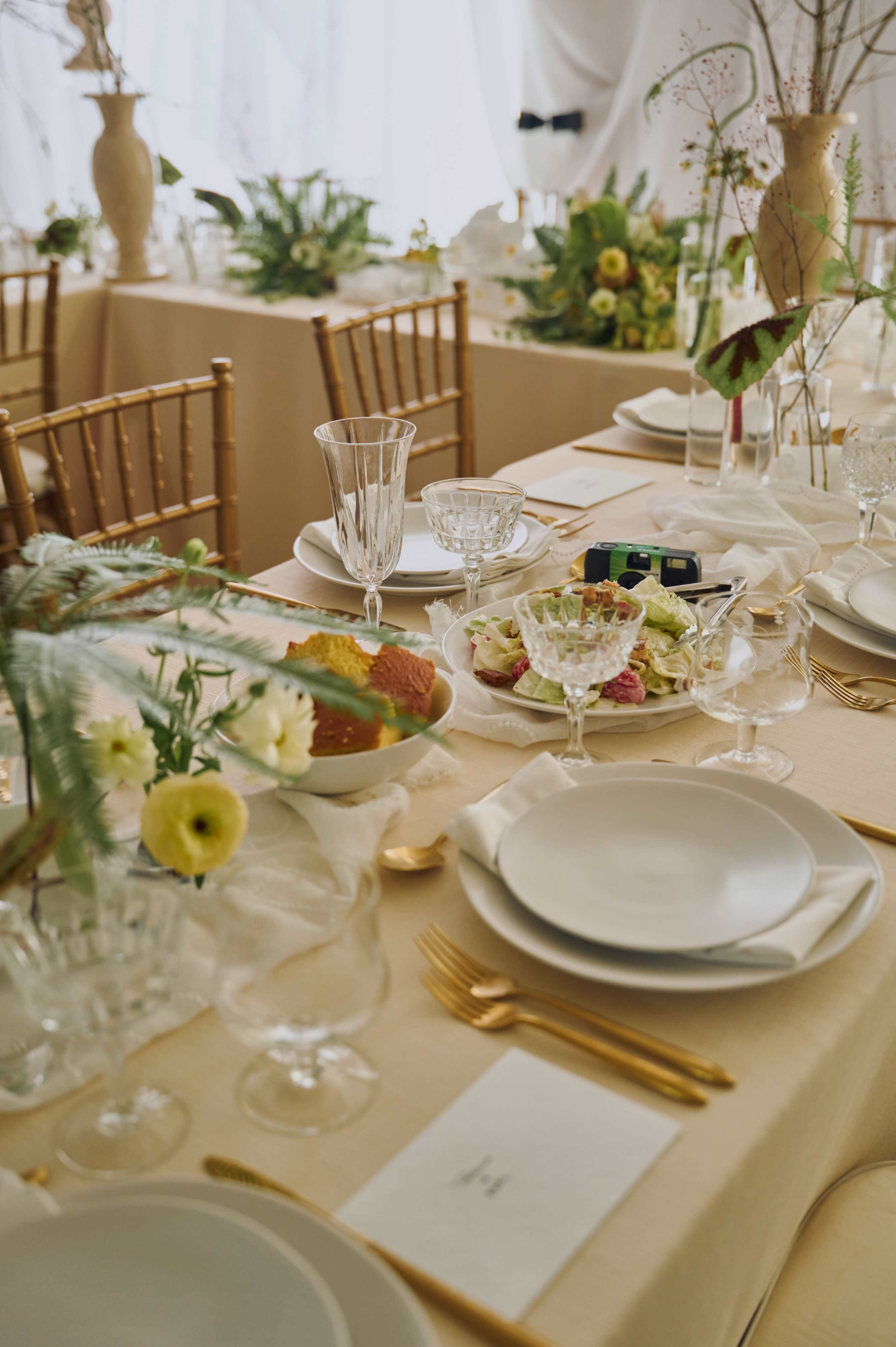 A dining table is set with elegant dishware, glassware, and floral arrangements for a formal event.