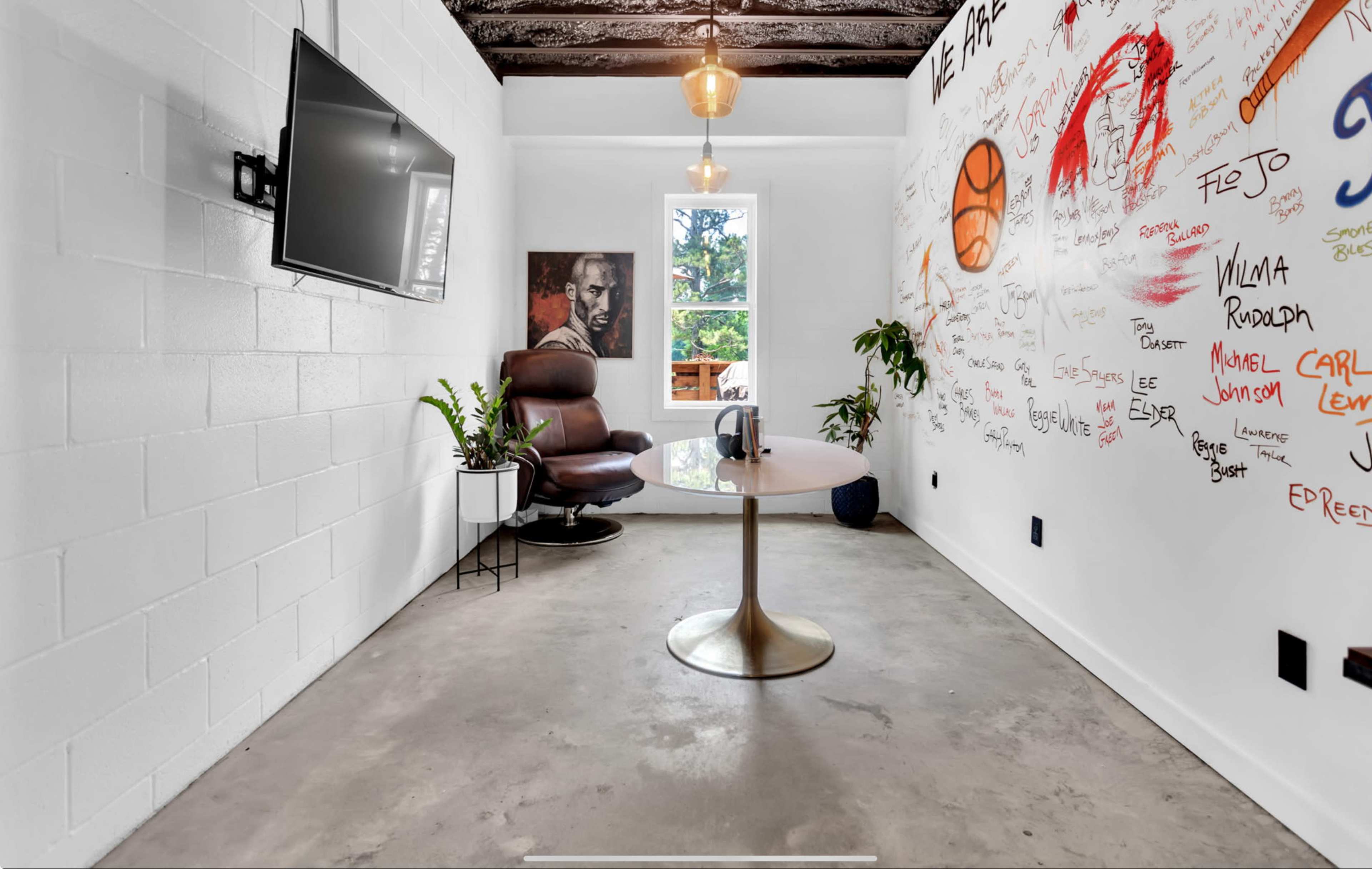 A small meeting room features a round table, a leather chair, and walls covered with colorful graffiti and drawings.