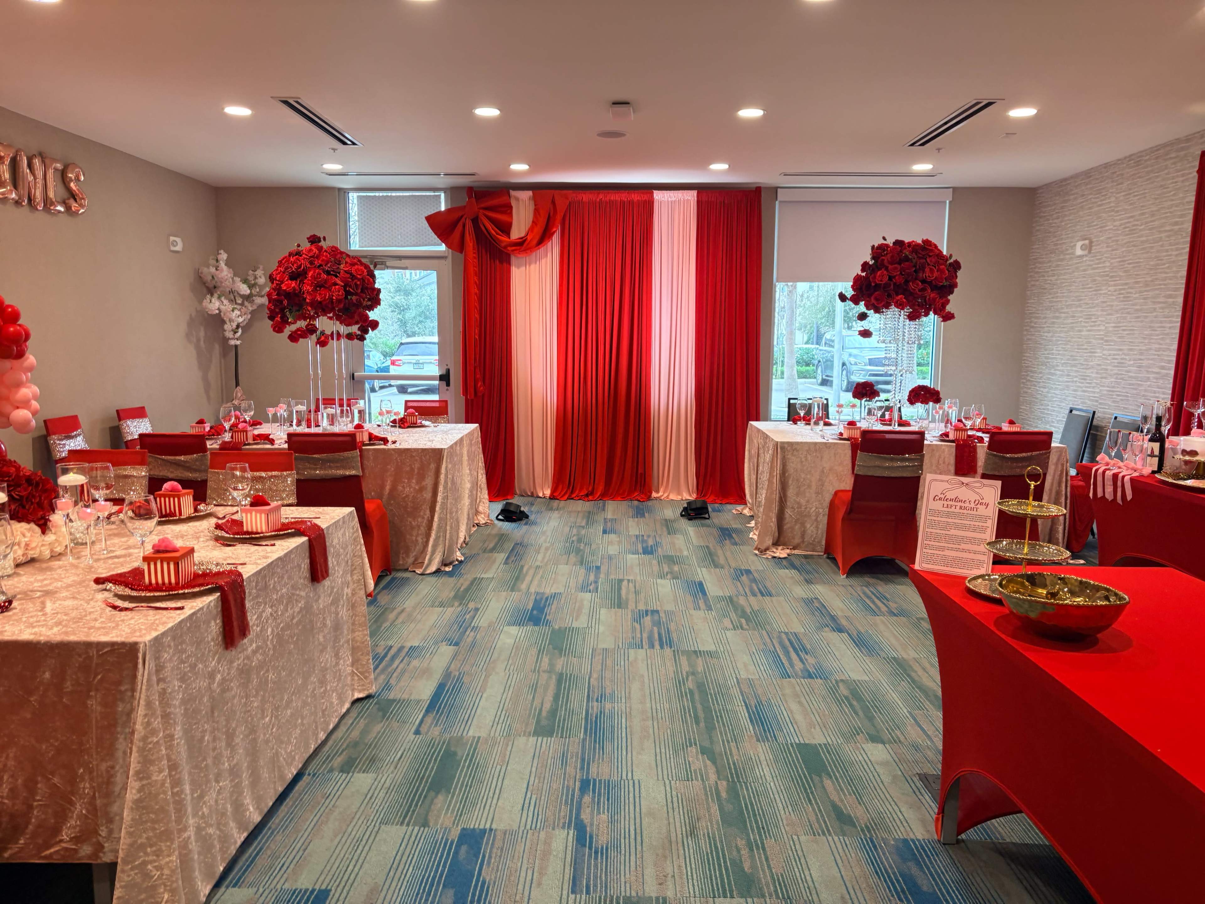 The image shows a decorated room set for a celebration with red and white table linens, floral centerpieces, and themed decorations.