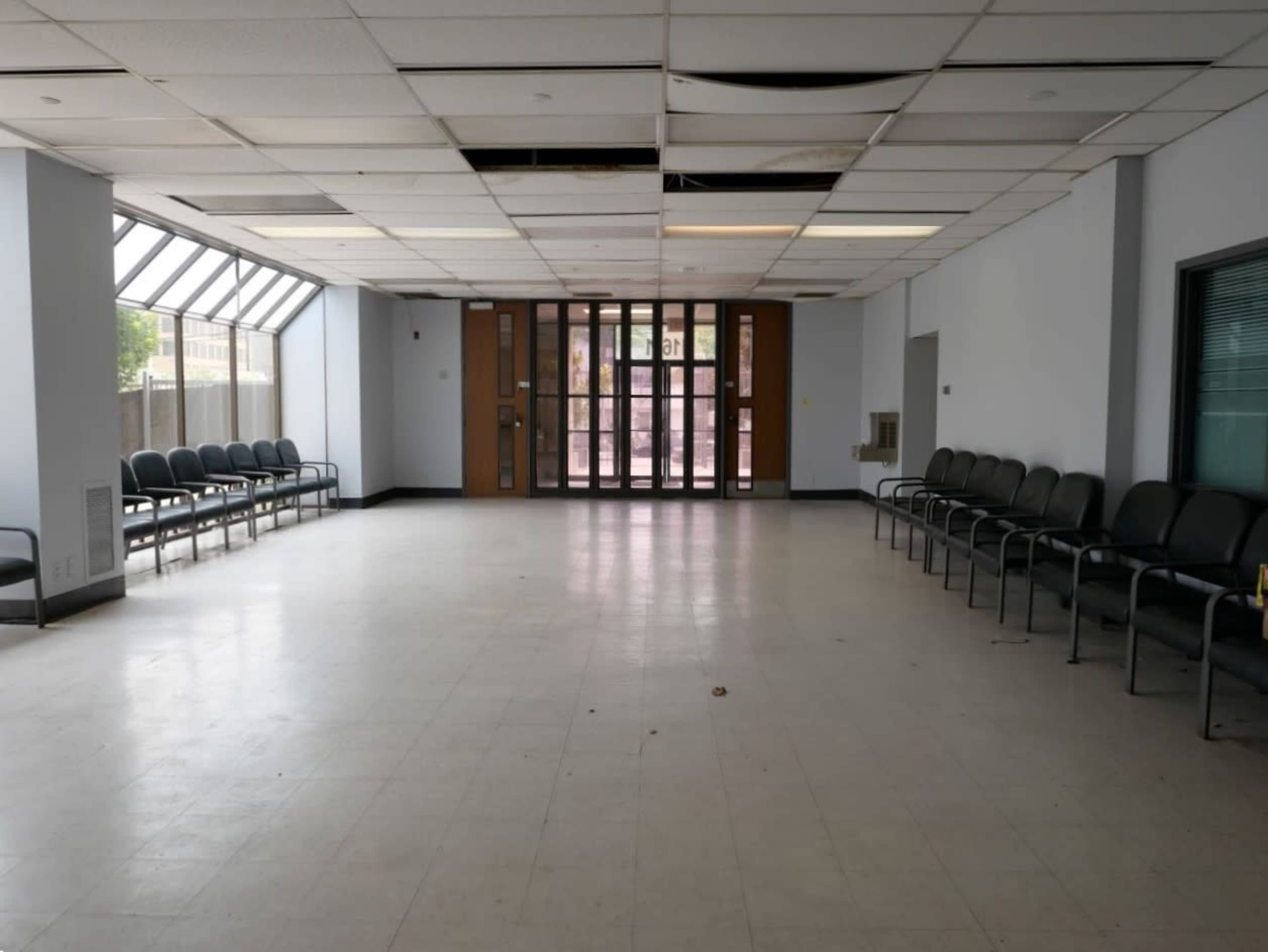 An empty waiting area features rows of chairs and large windows along one side.