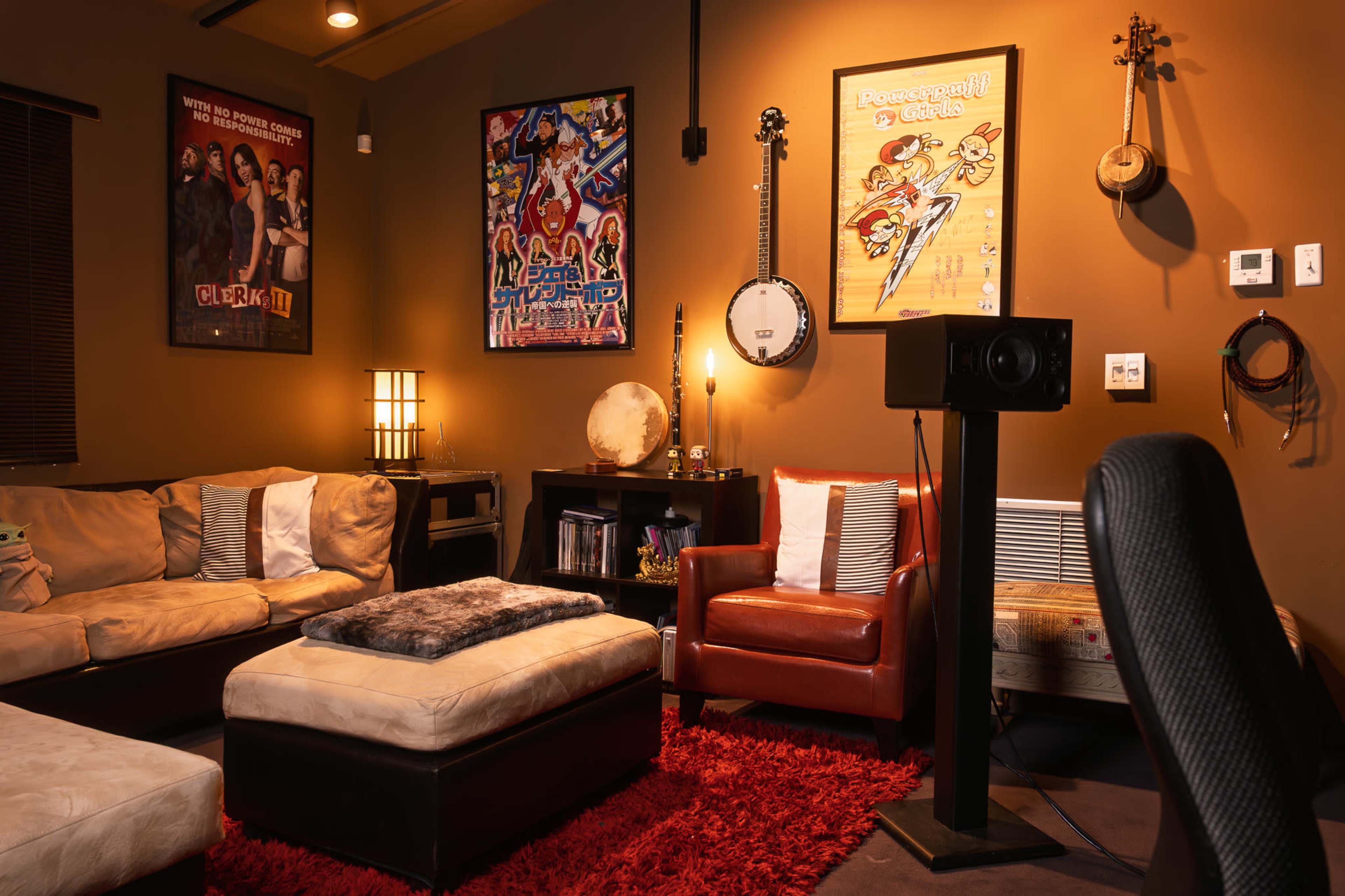 The room features a cozy seating area with a brown couch, red armchair, and coffee table, adorned with colorful artwork on the walls and a soft red rug on the floor.