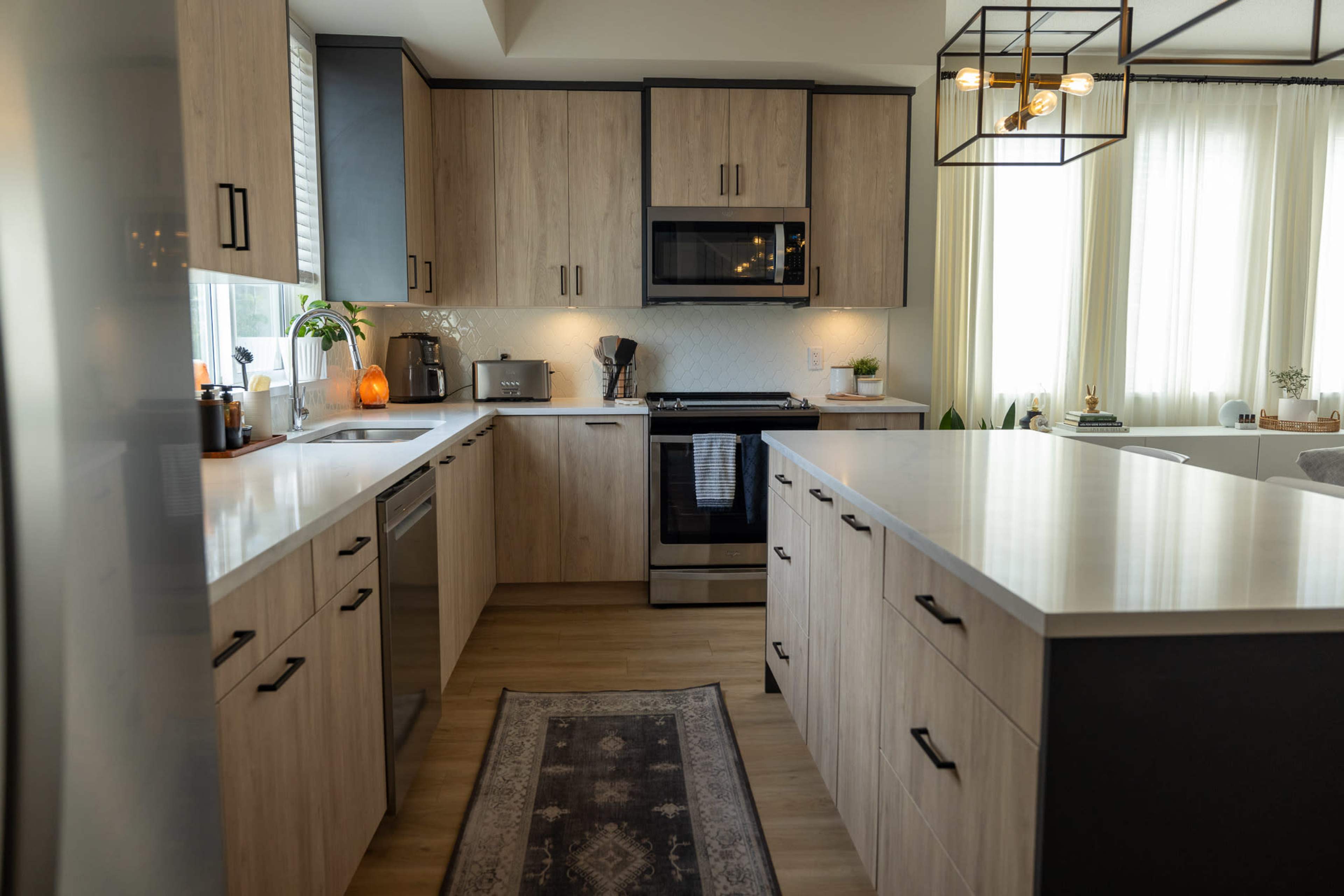 A modern kitchen with wood cabinetry, stainless steel appliances, and a central island with a white countertop.