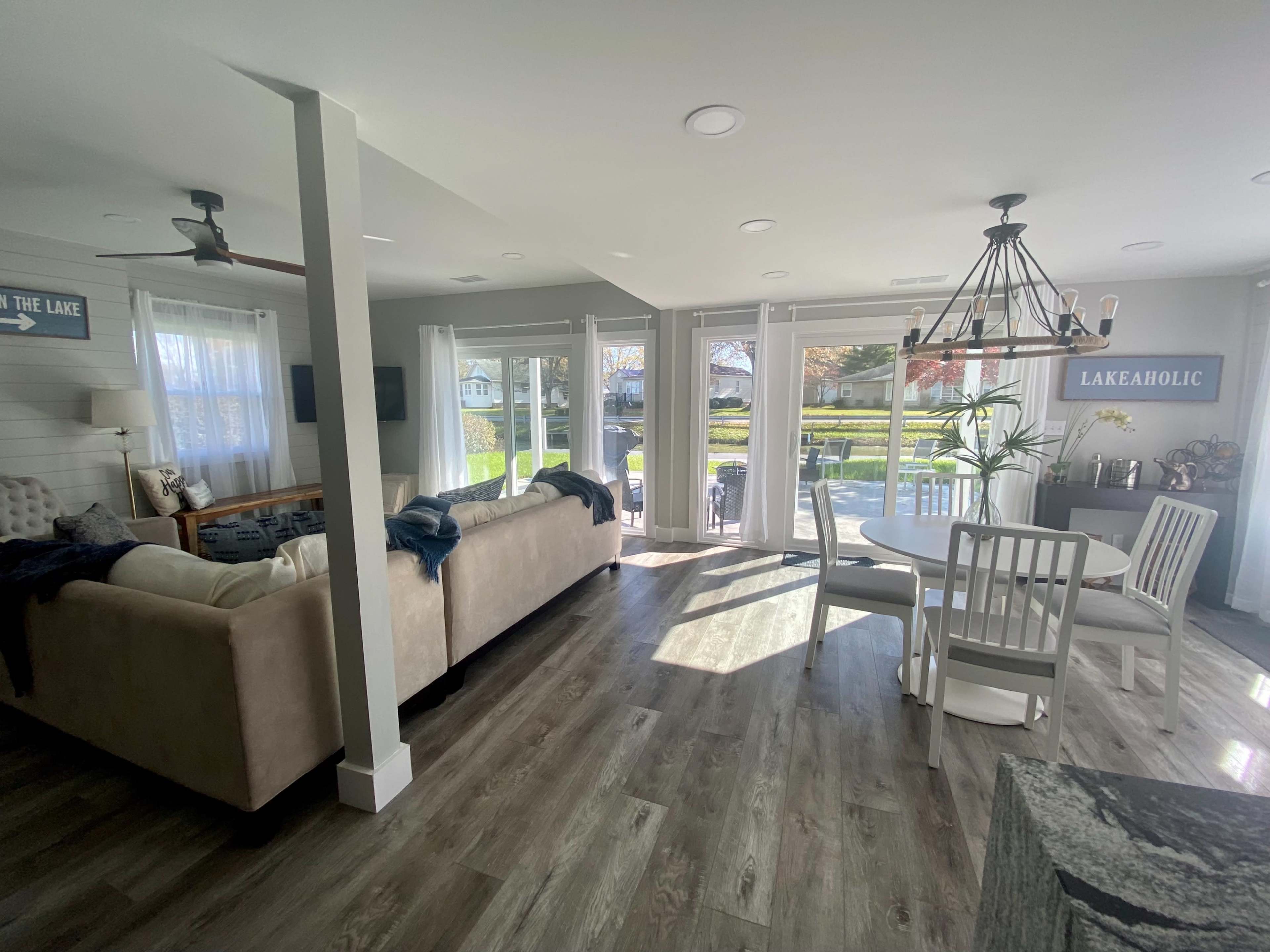 A bright, open-concept living area with a sofa, dining table, and large windows that provide a view of an outdoor patio.