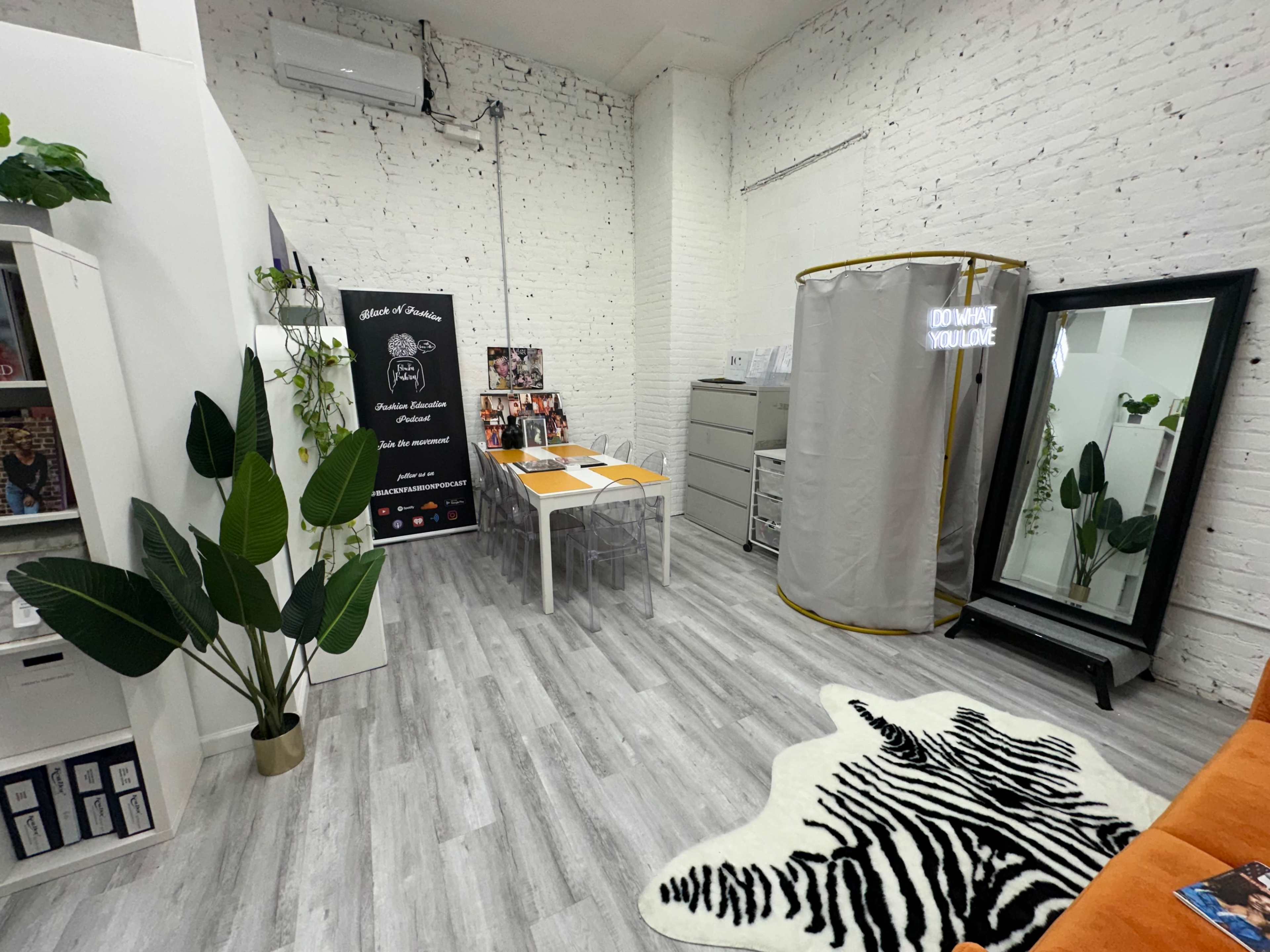 A bright, modern office space featuring a table with orange chairs, a large mirror, and a folding partition.