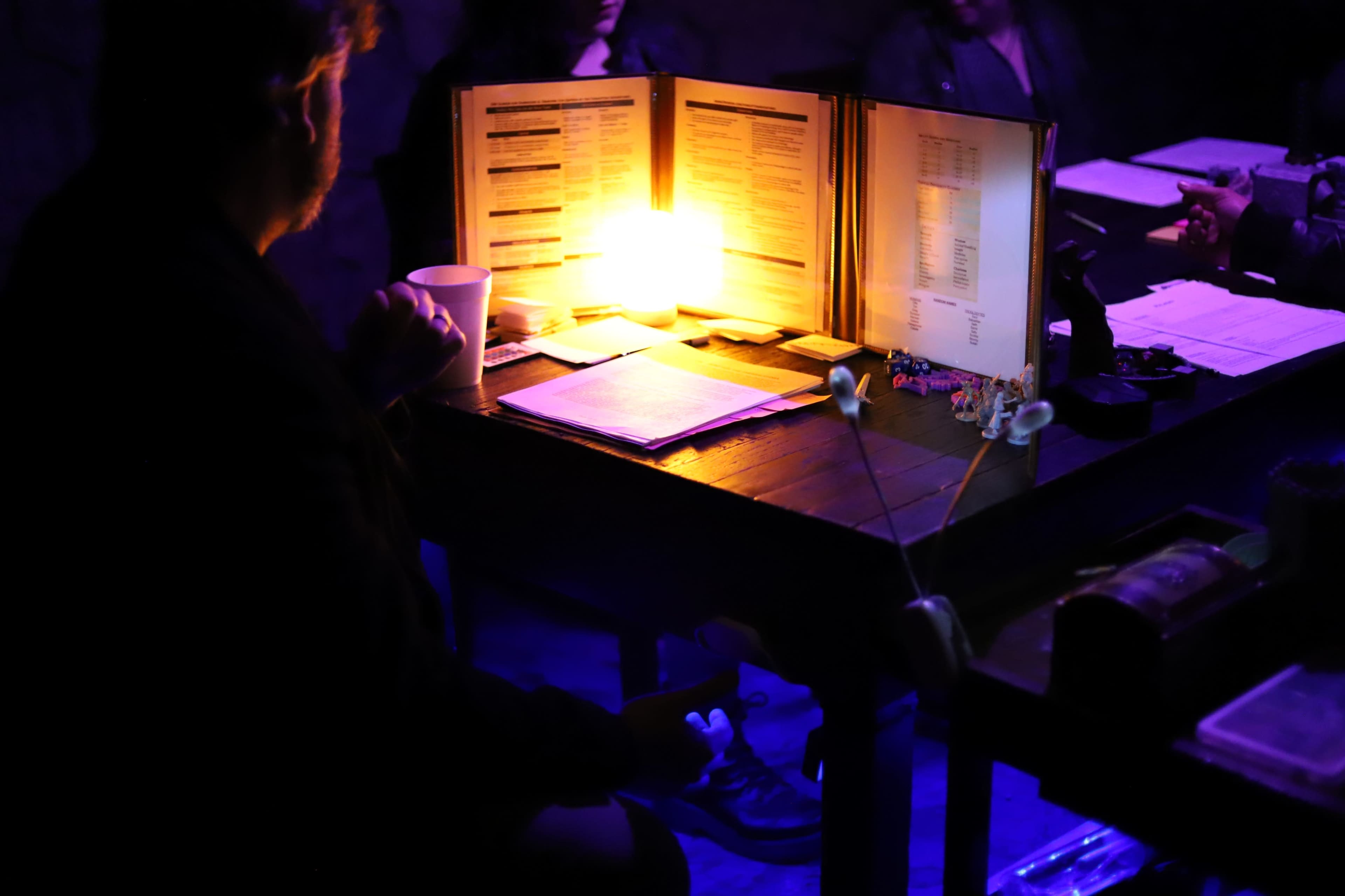 A dimly lit table with an illuminated menu surrounded by people engaged in conversation.