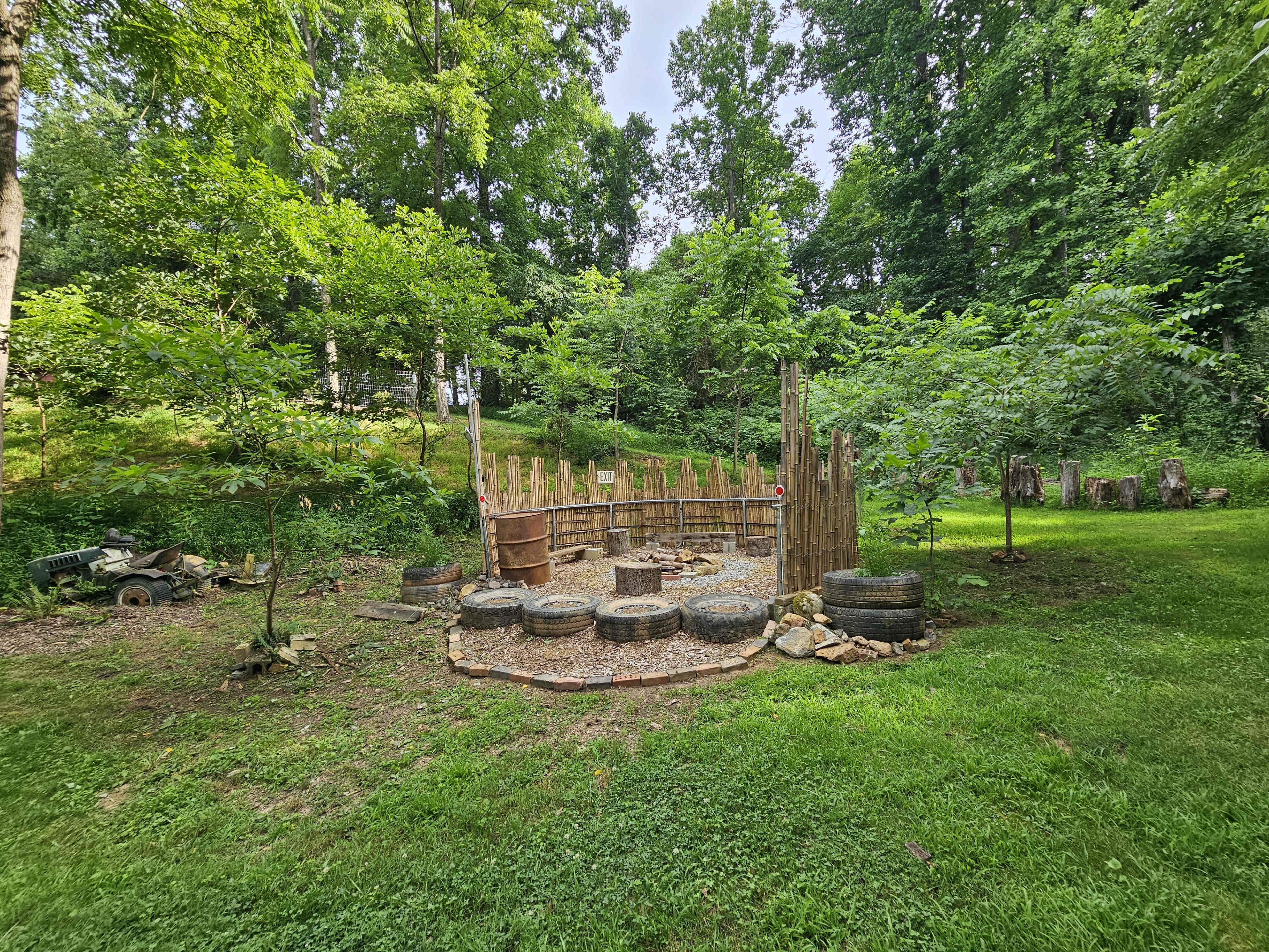 The scene shows a fenced garden area surrounded by greenery, featuring a circular layout with tires and a wooden structure in the center.