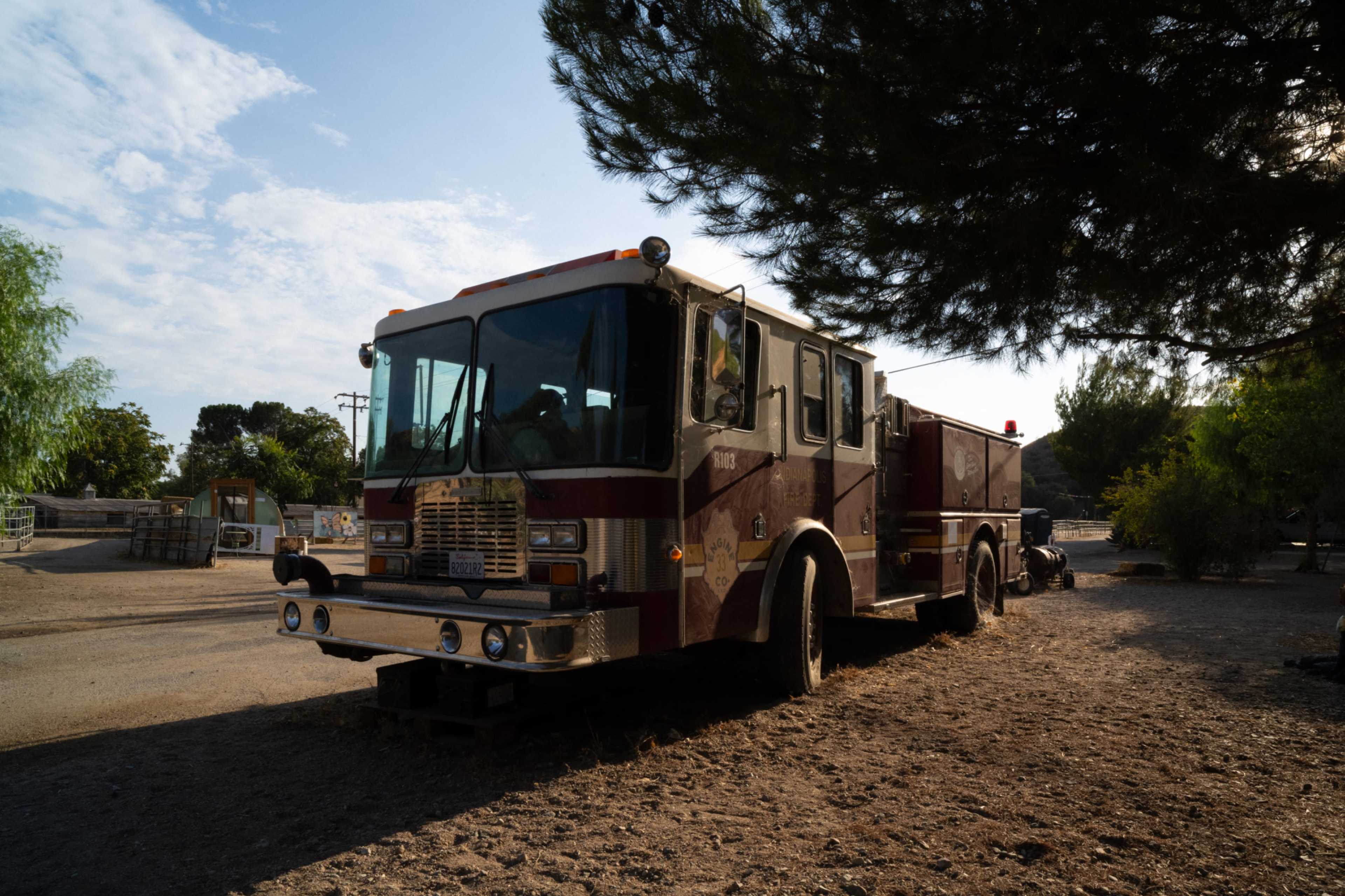 A fire truck is parked on a dirt lot surrounded by trees and utility poles.