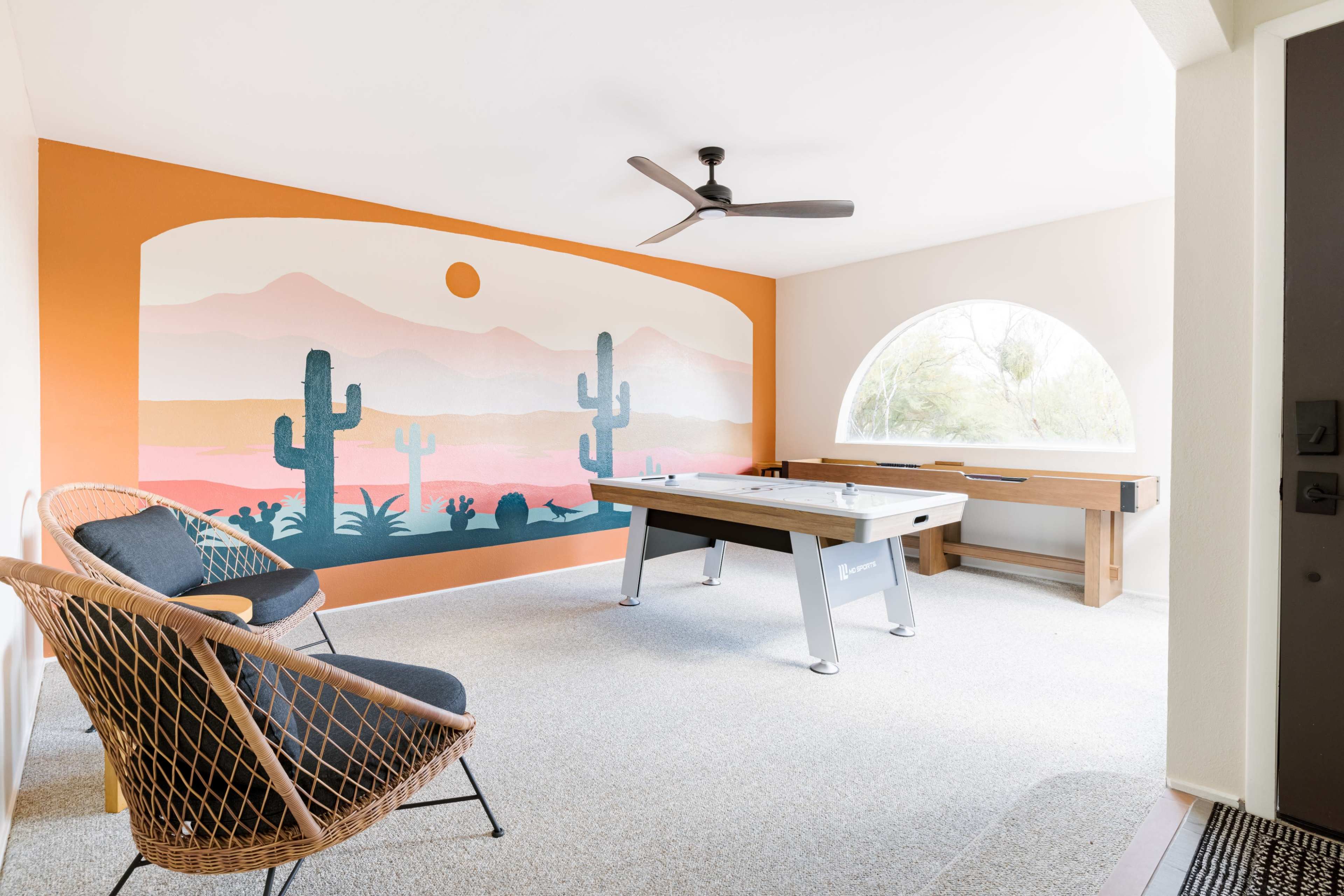 The room features a pool table, a large window, and a mural depicting a desert landscape with cacti and mountains.