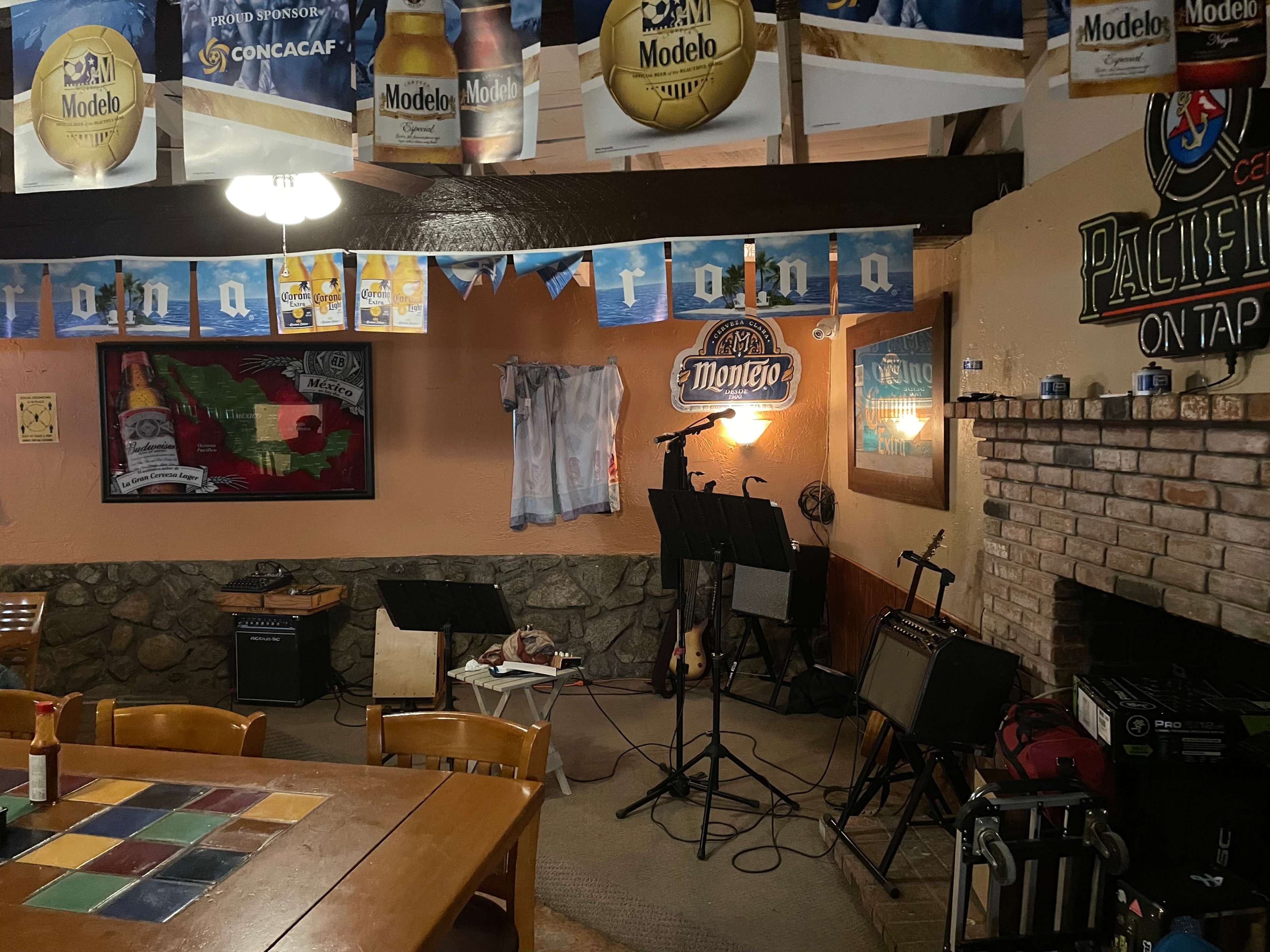 A rustic interior of a bar or restaurant featuring musical instruments, decorations, and various beer advertisements on the walls.