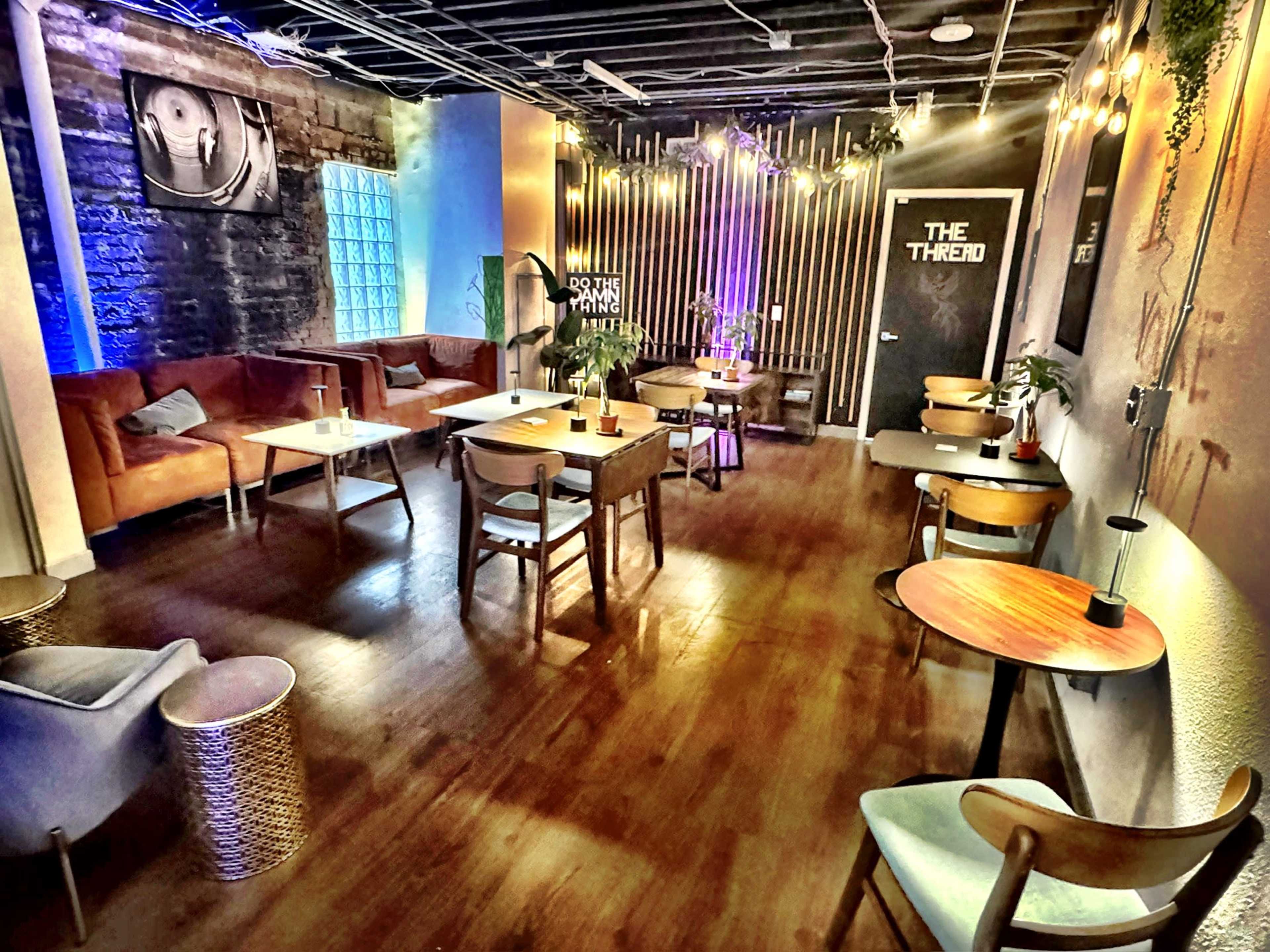 The image shows a modern lounge space with wooden flooring, various seating arrangements, and ambient lighting features.