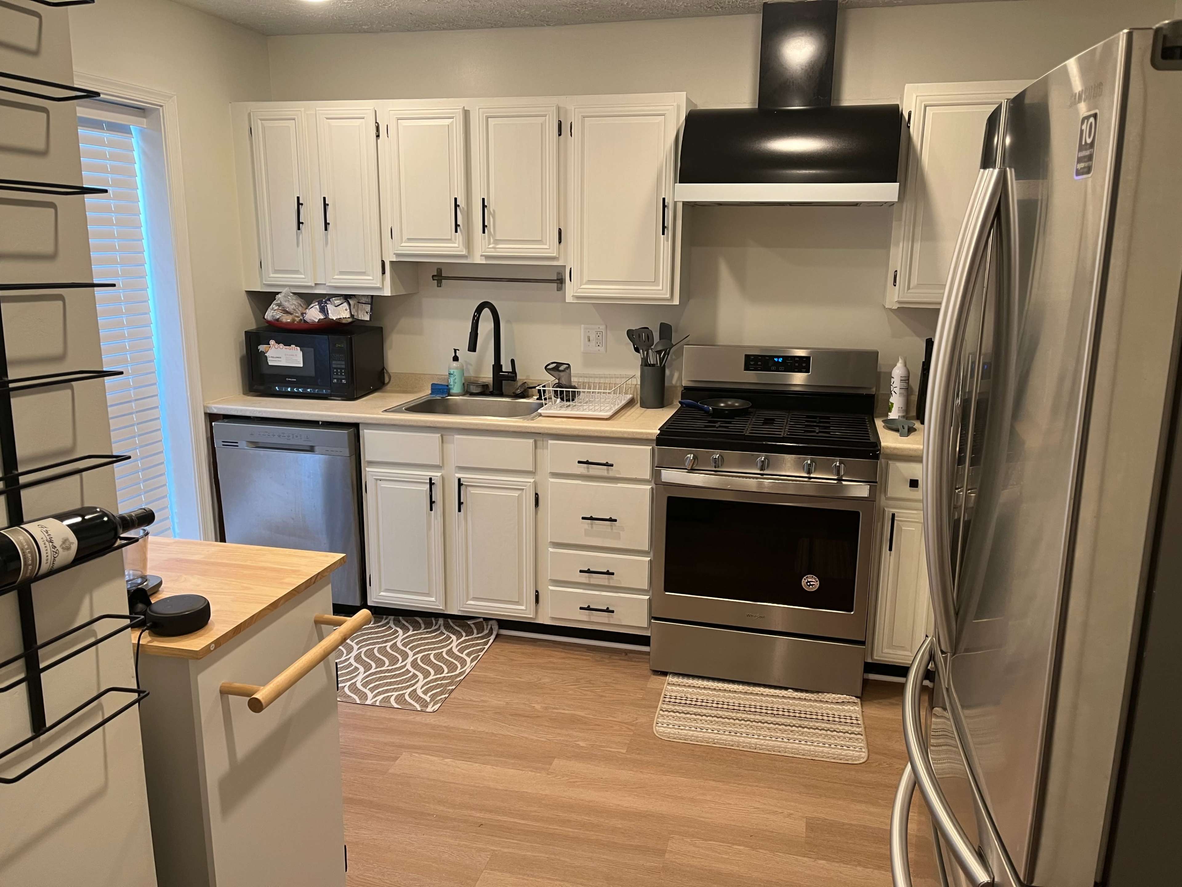 A modern kitchen features white cabinets, stainless steel appliances, and a light-colored wood floor.