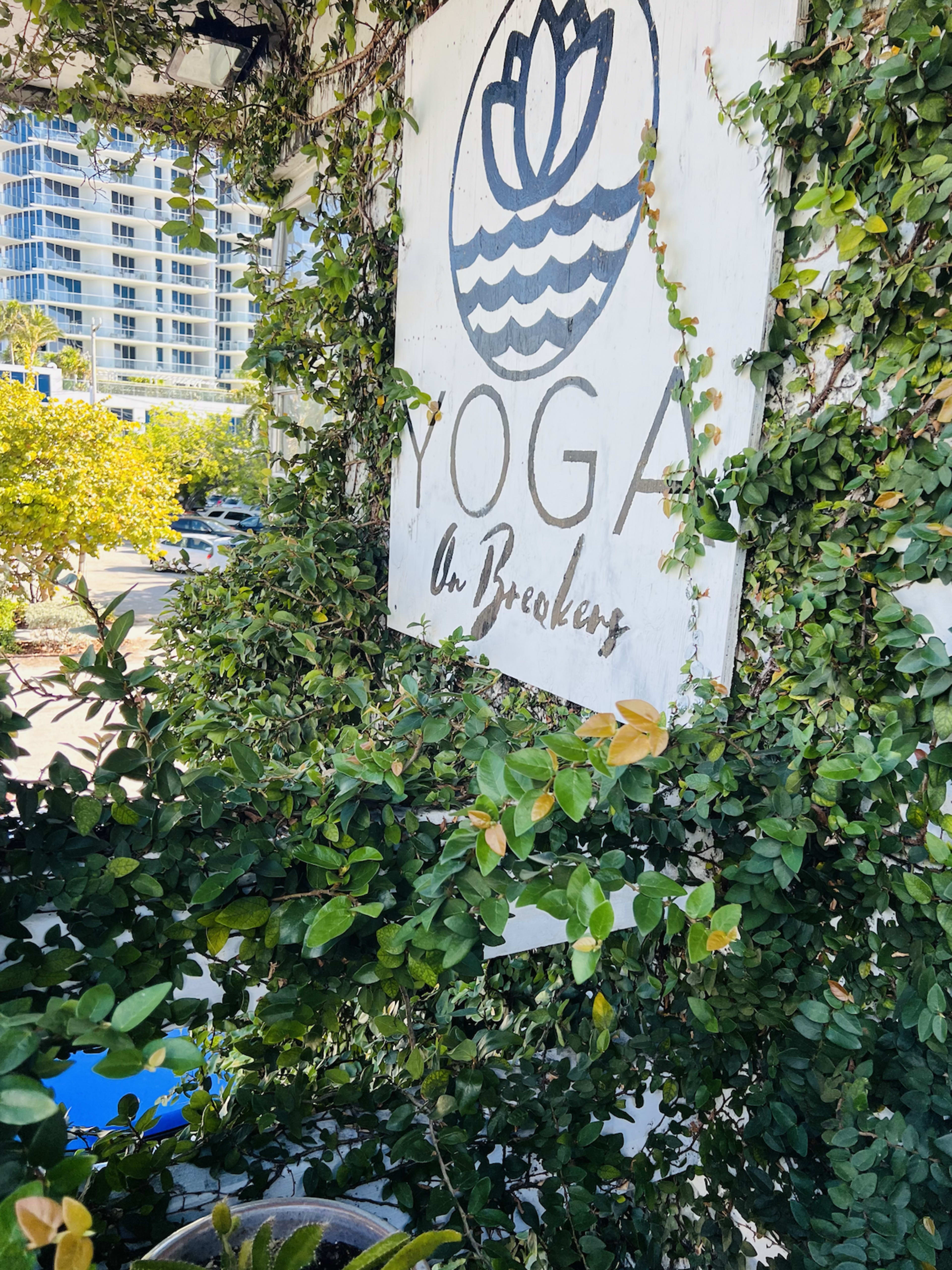 A weathered sign reading "Yoga at Breakers" is partially obscured by lush green vines.