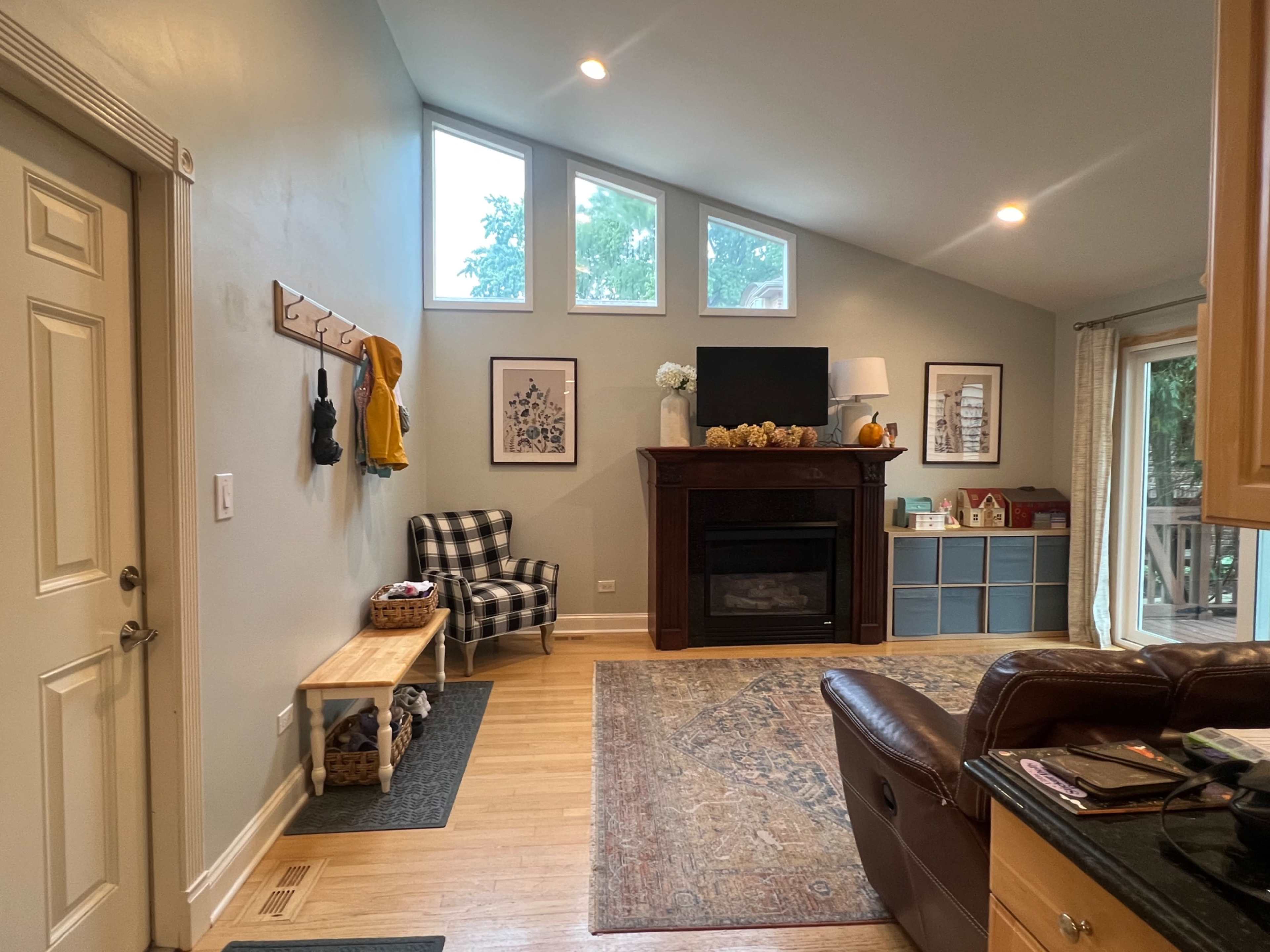 The image shows a living room with a fireplace, a seating area, and a door leading outdoors.