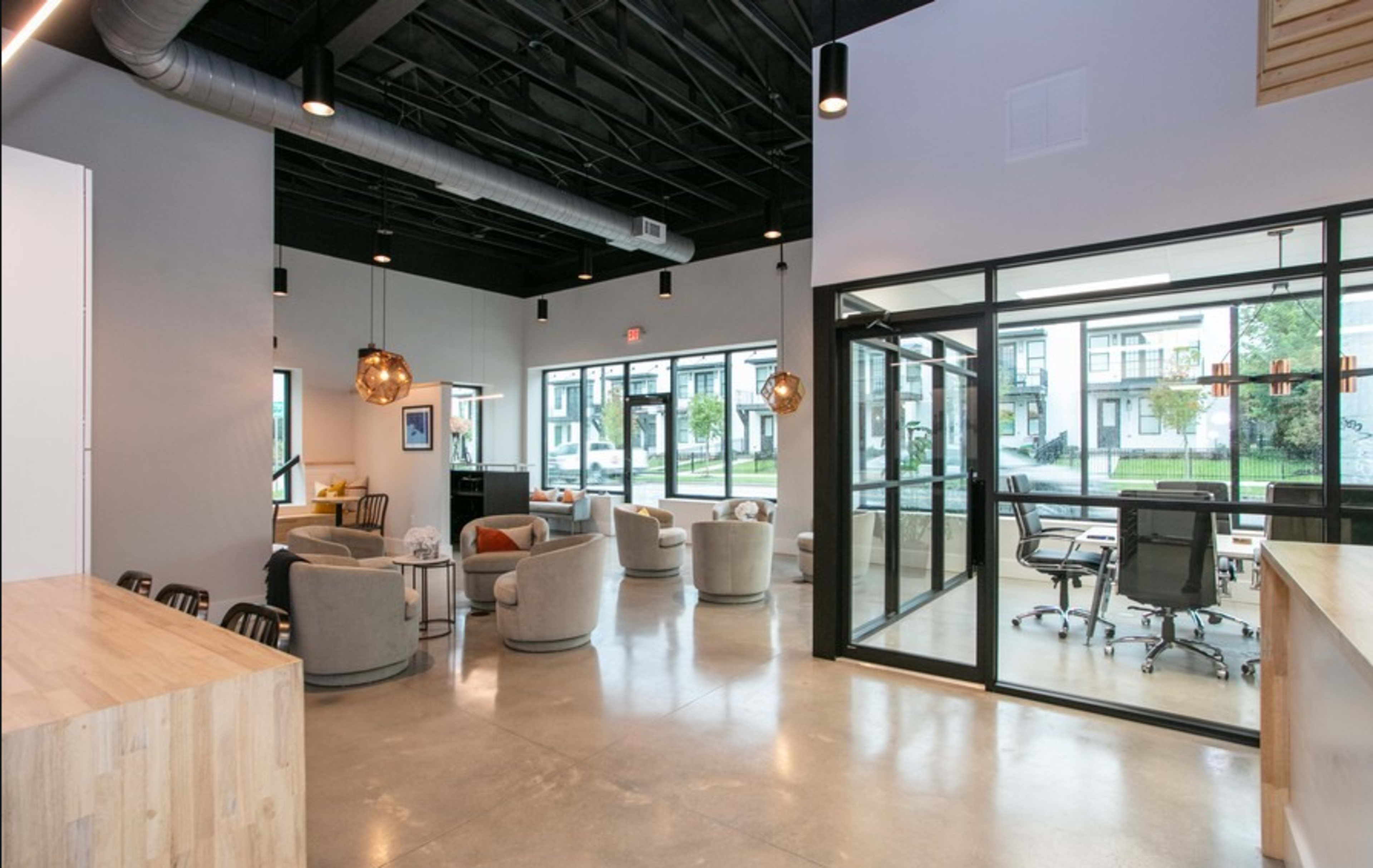 A modern office space featuring a seating area with circular chairs, large windows, and a glass-walled conference room.