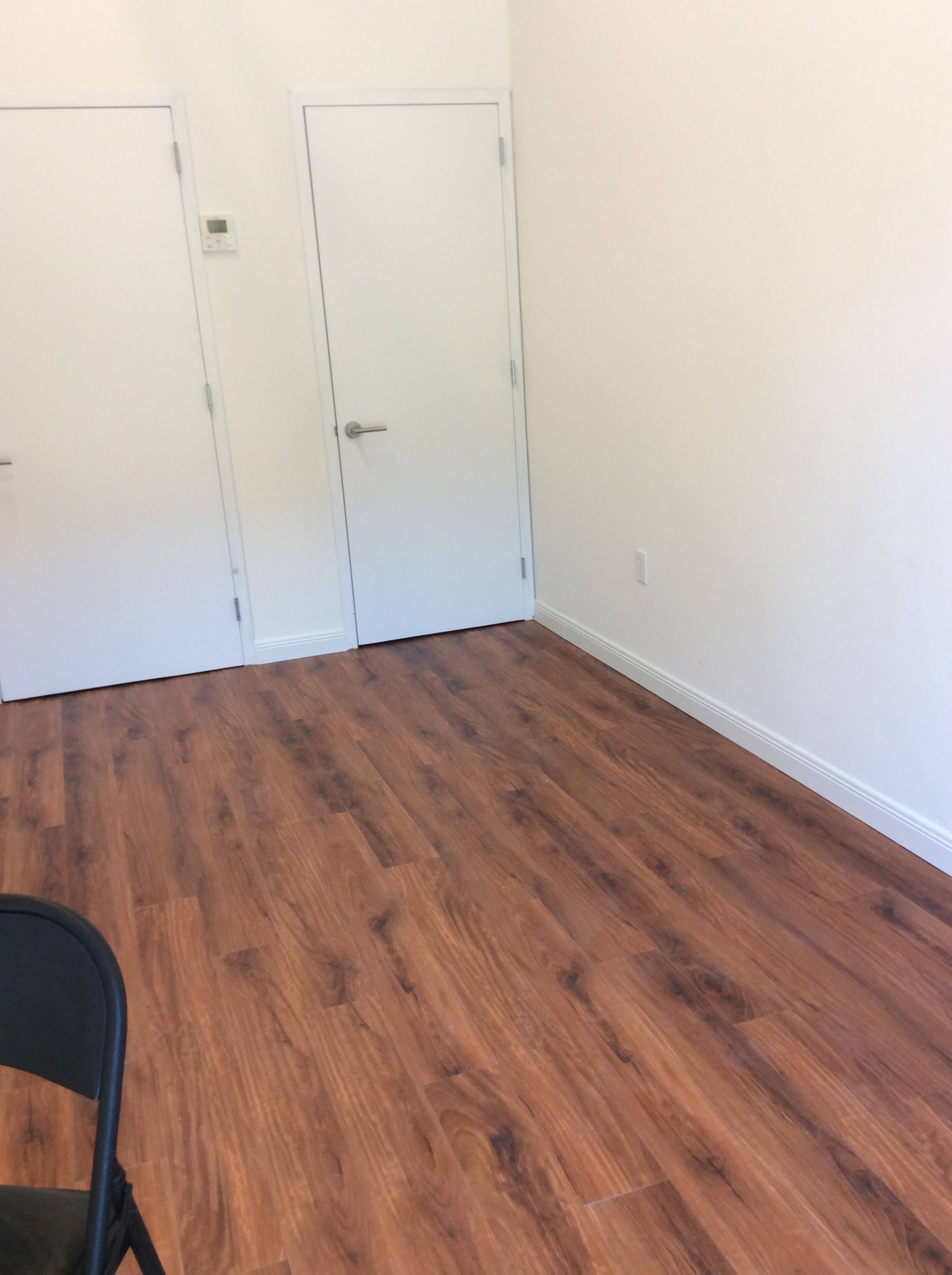A minimal room with two closed white doors and a wooden laminate floor.