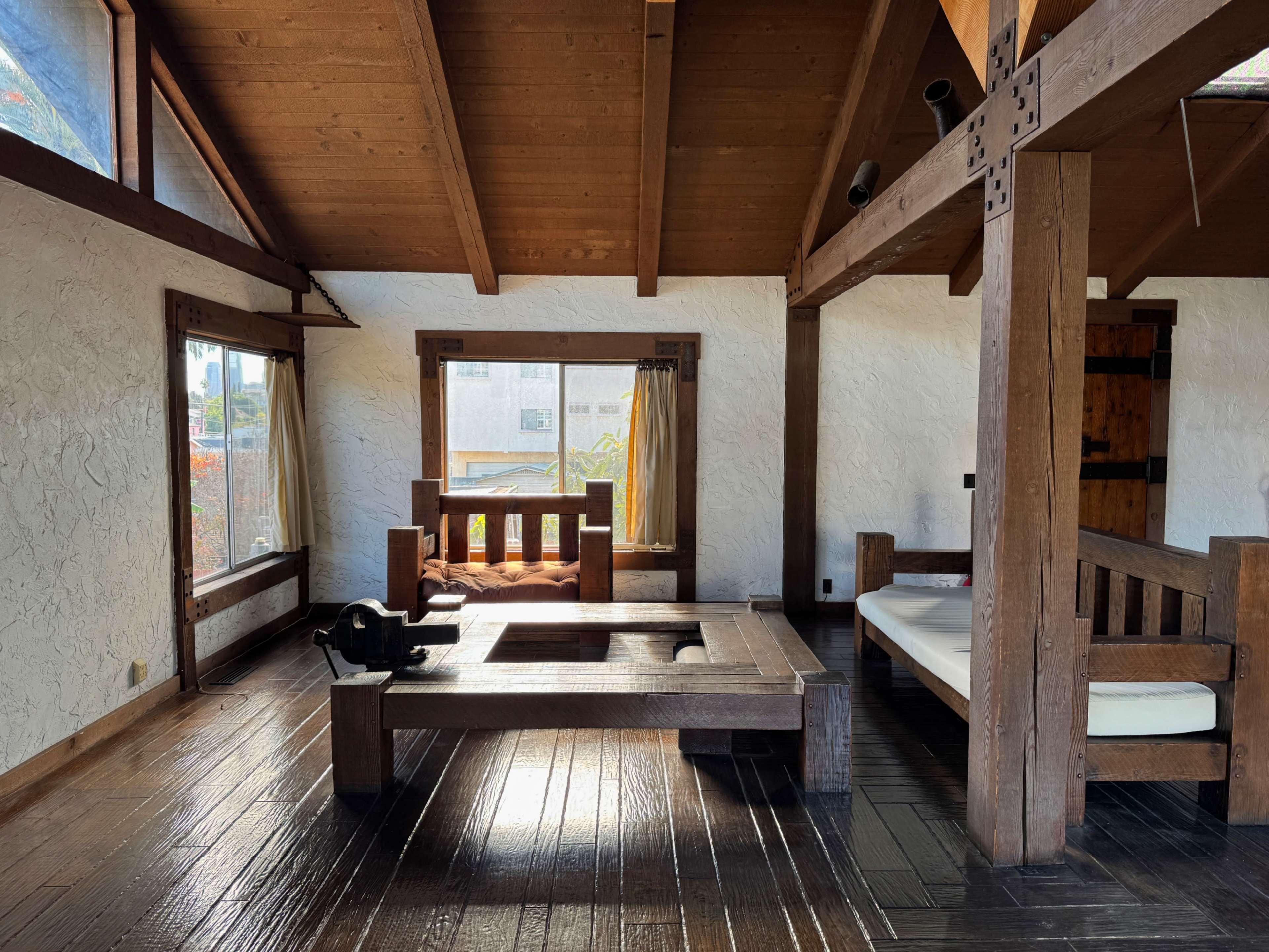 The interior of a wooden cabin features a spacious, open layout with large windows, traditional furniture, and exposed beams.