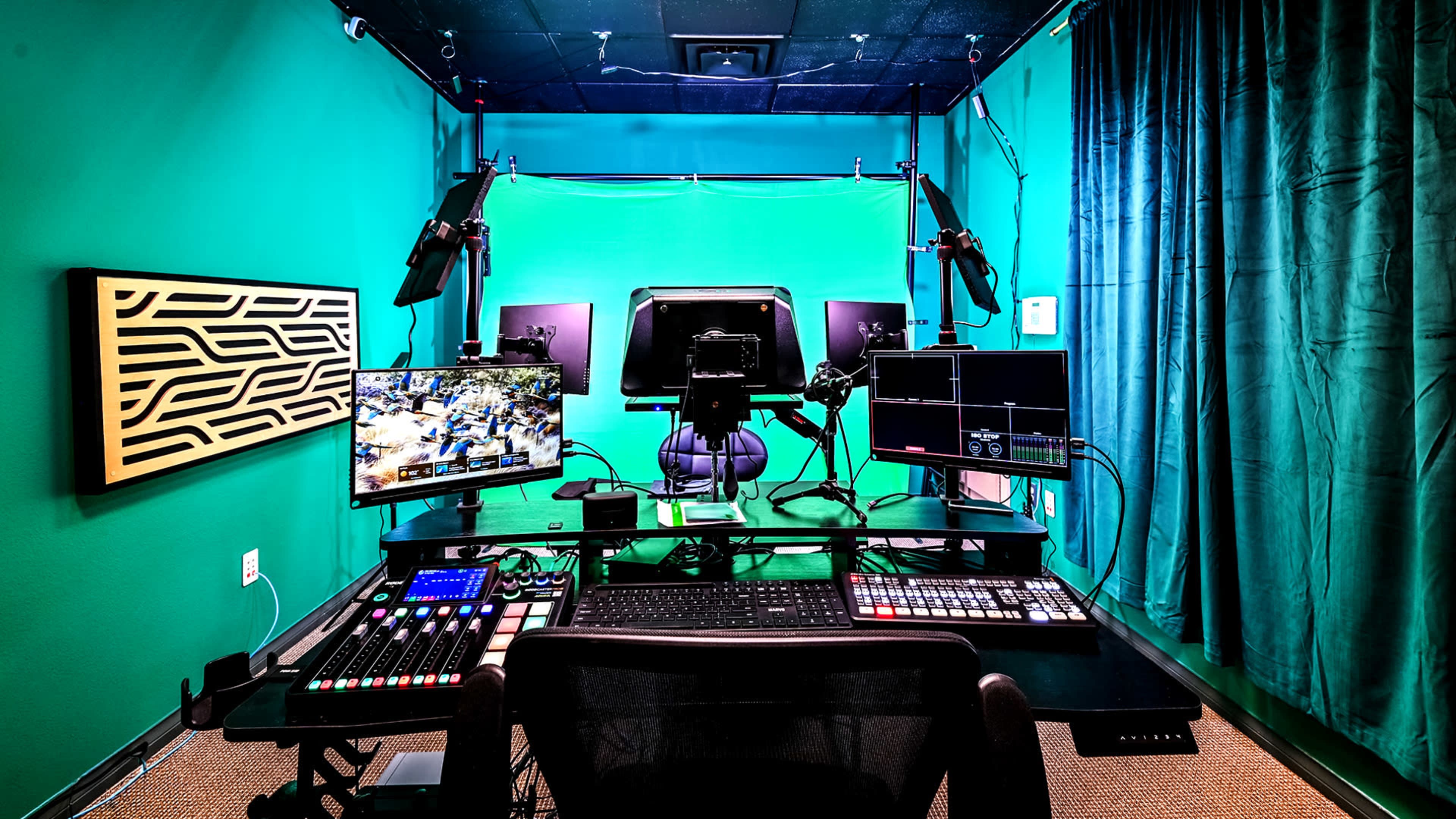 A modern video production studio features multiple screens, audio equipment, and a prominent green screen backdrop.