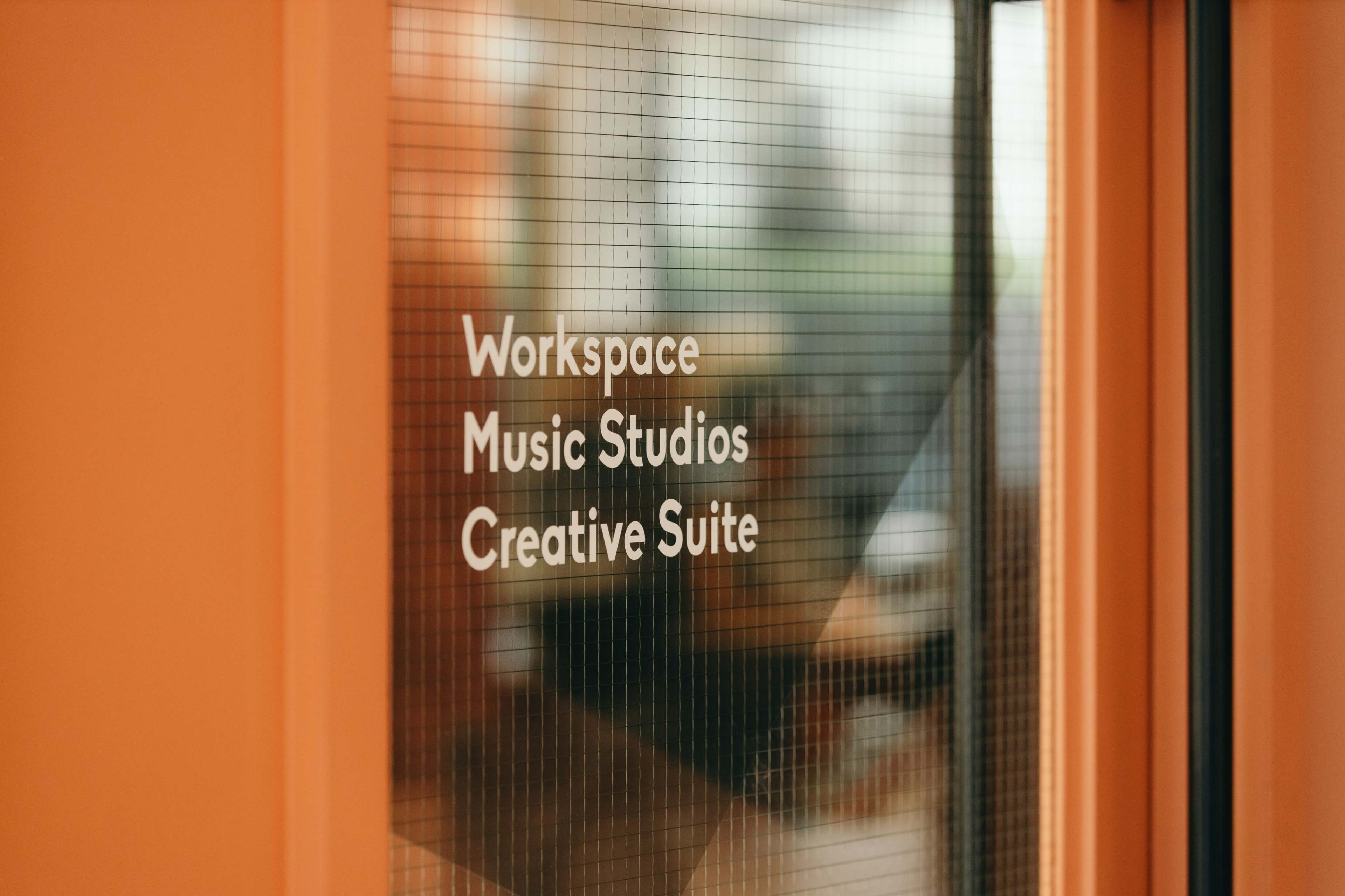 A glass door with the text "Workspace Music Studios Creative Suite" displayed on it.
