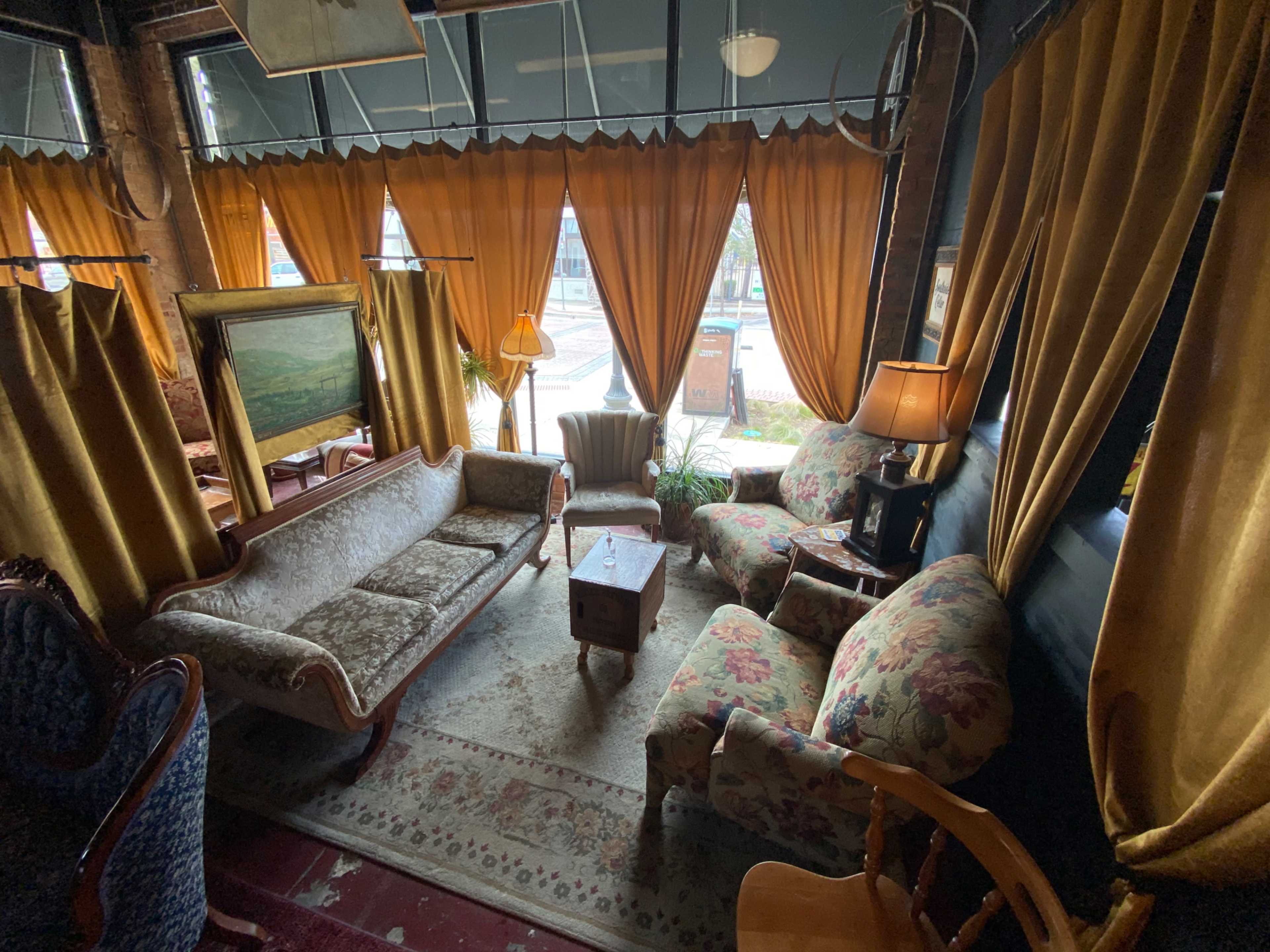 A cozy sitting area with floral-patterned furniture, warm curtains, and a rug on the floor.