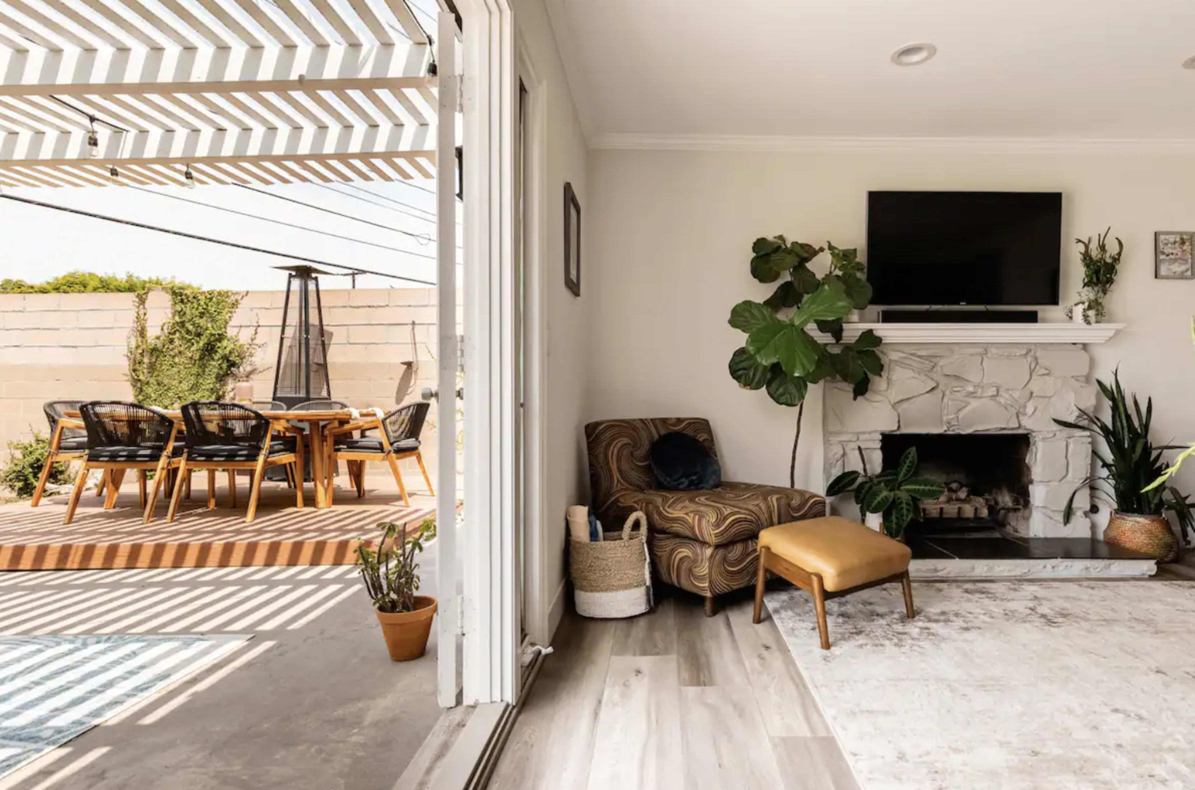 A cozy living room features a comfortable chair and television, with an open doorway leading to an outdoor dining area on a wooden deck.