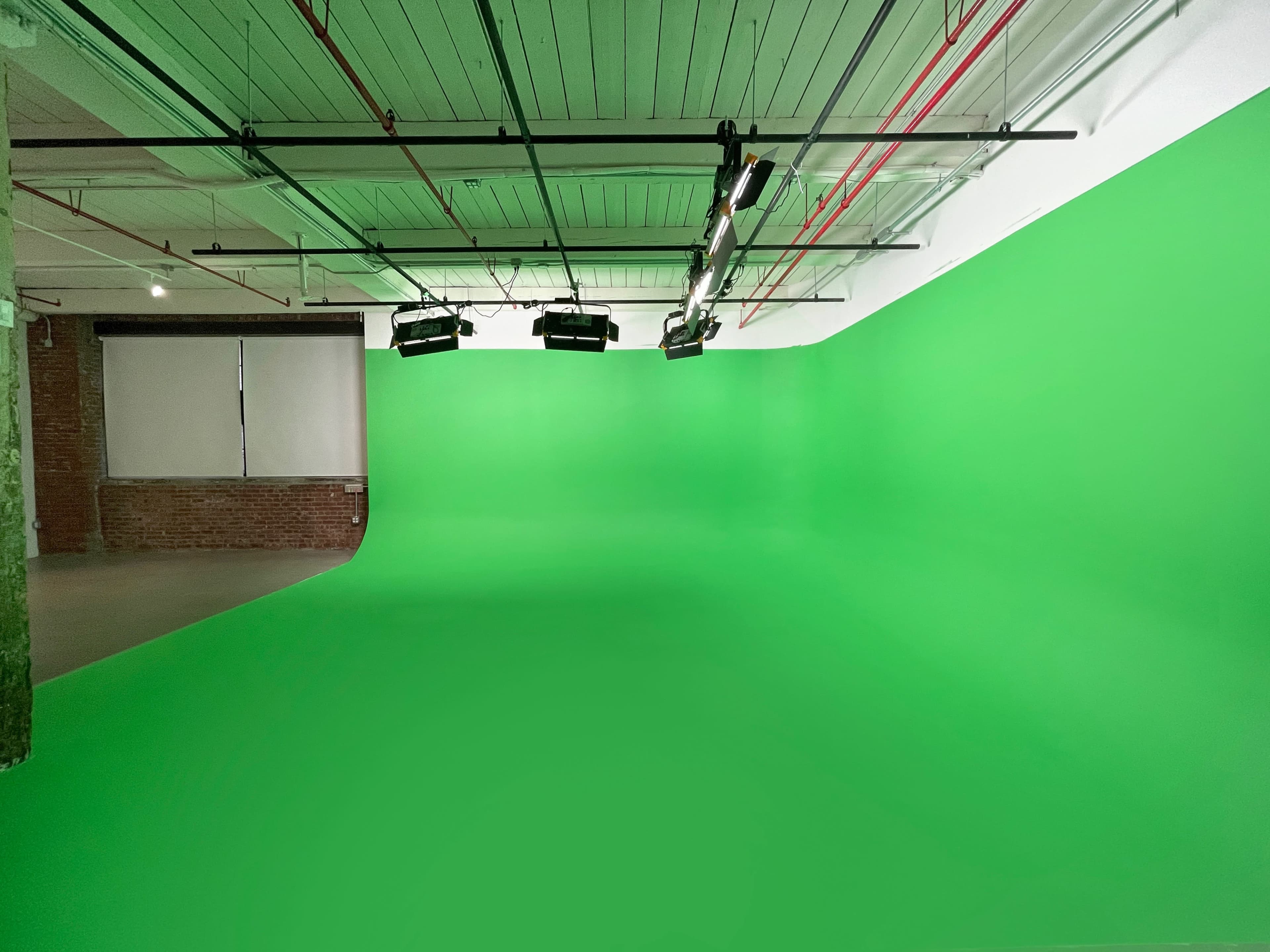 A green screen studio with a seamless green backdrop and overhead lighting.
