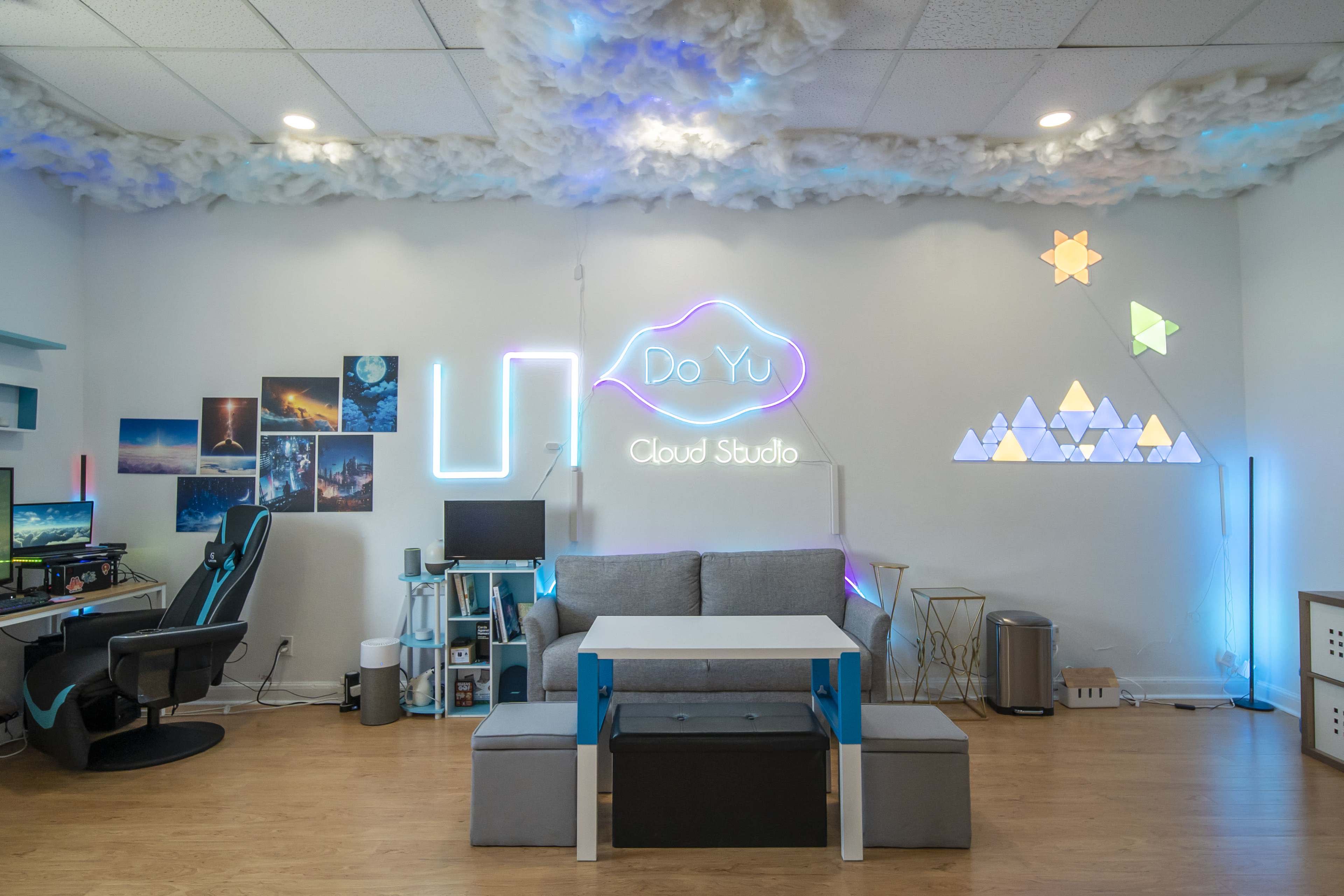 A modern creative workspace featuring a couch, a table, colorful wall decorations, and a desk setup with computers.
