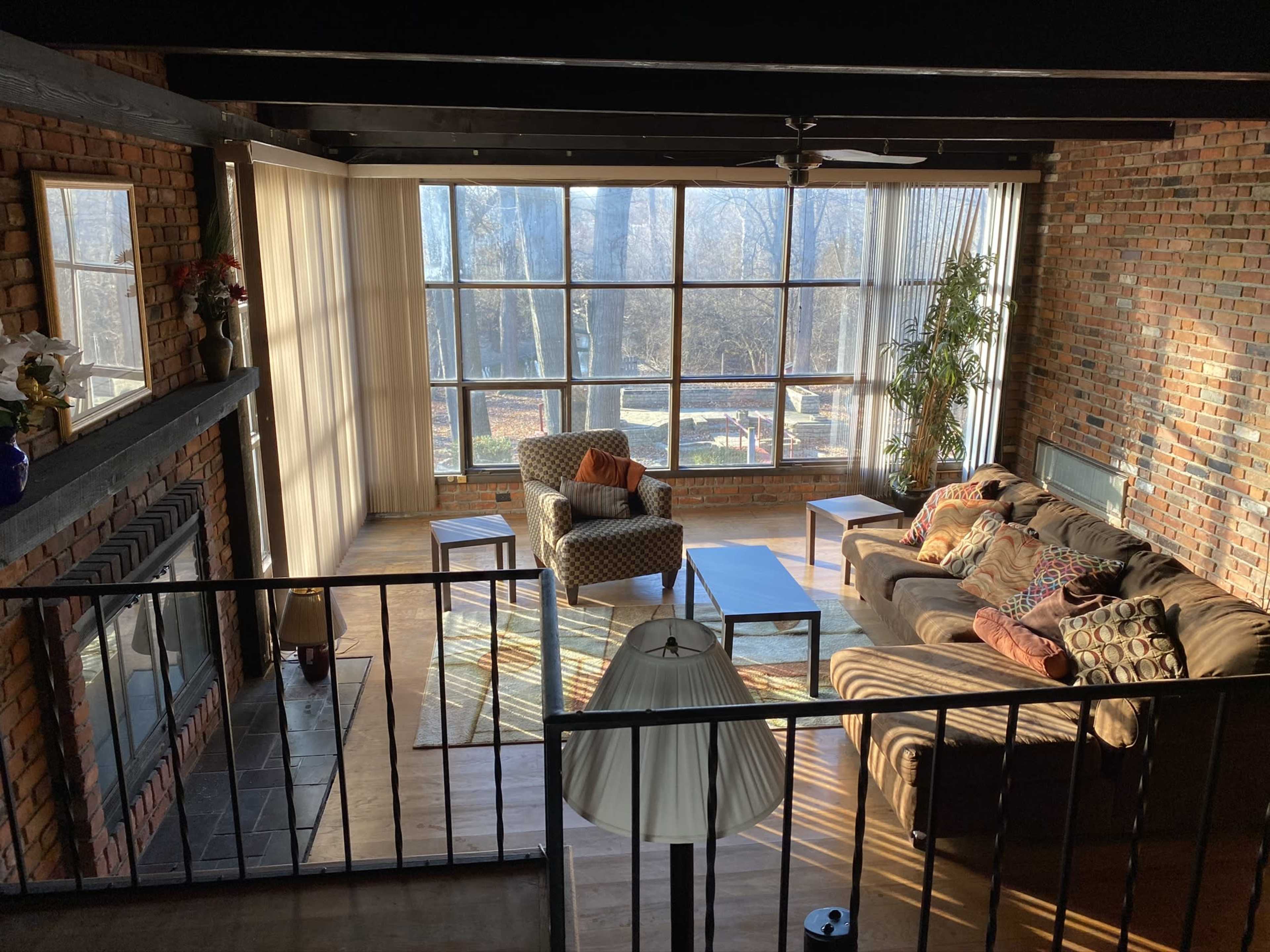 A spacious living room with large windows, a mix of seating options, a coffee table, and a view of a landscaped area outside.