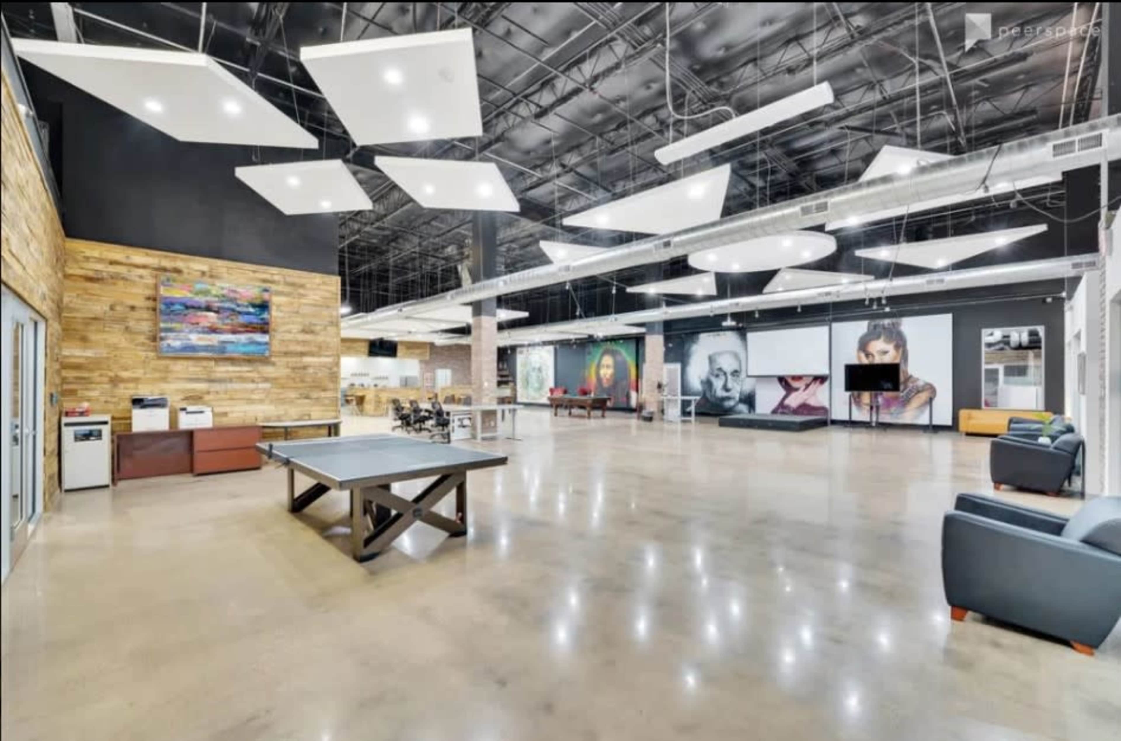 The image shows a large, modern open space with polished concrete floors, a billiards table, and various wall-mounted artworks.