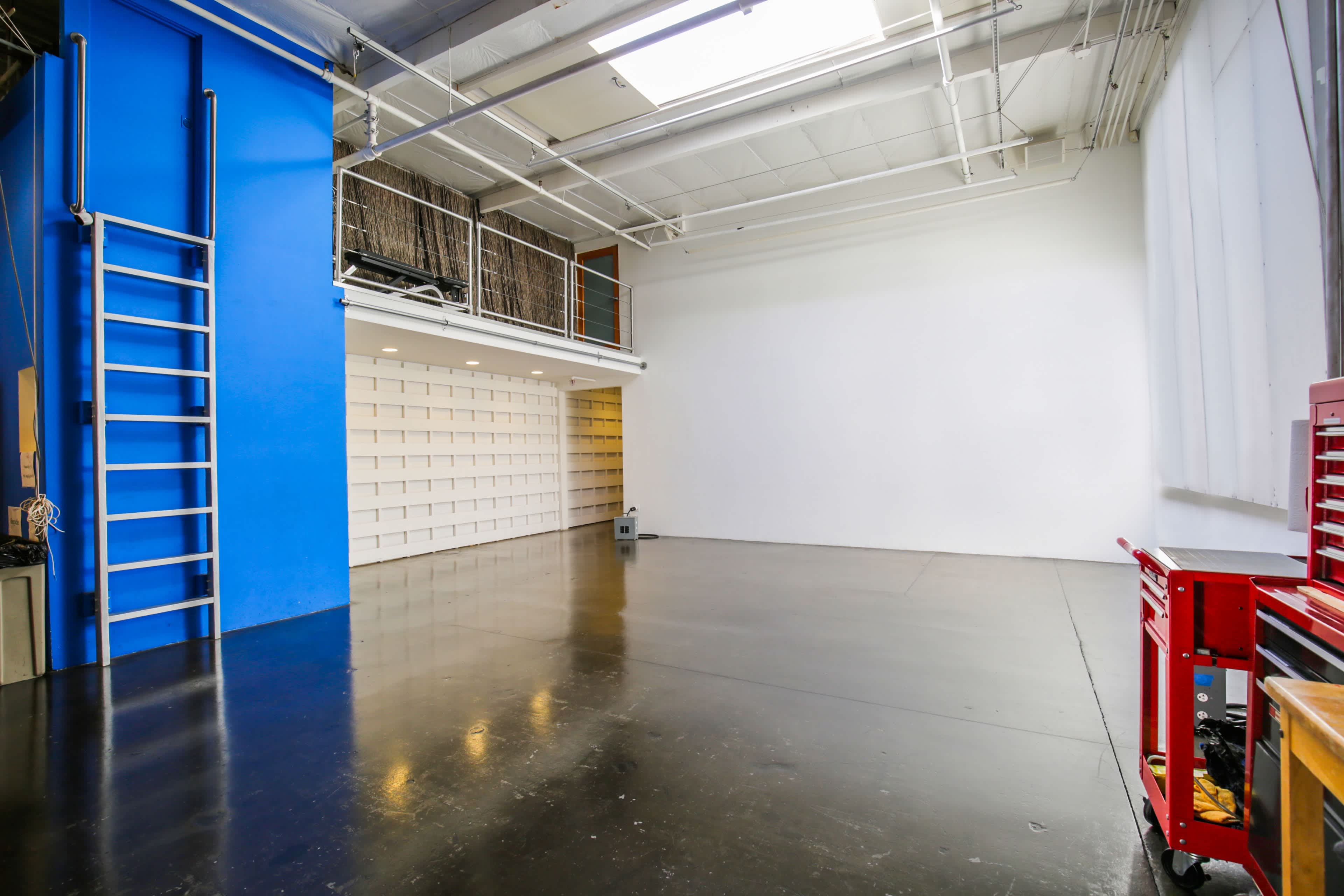 A spacious, empty studio with a blue wall on one side and a polished black floor.