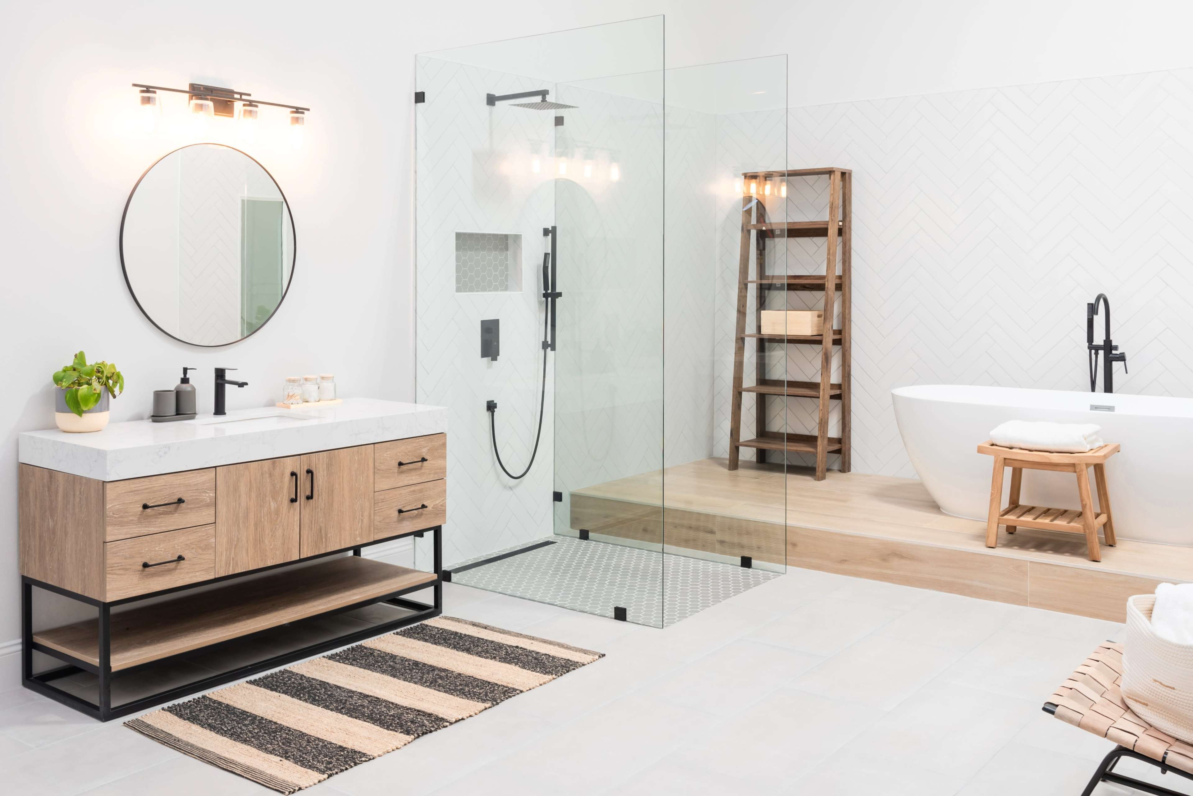 A modern bathroom featuring a freestanding bathtub, a glass shower enclosure, a wooden vanity with a white countertop, and a decorative shelf against a textured wall.