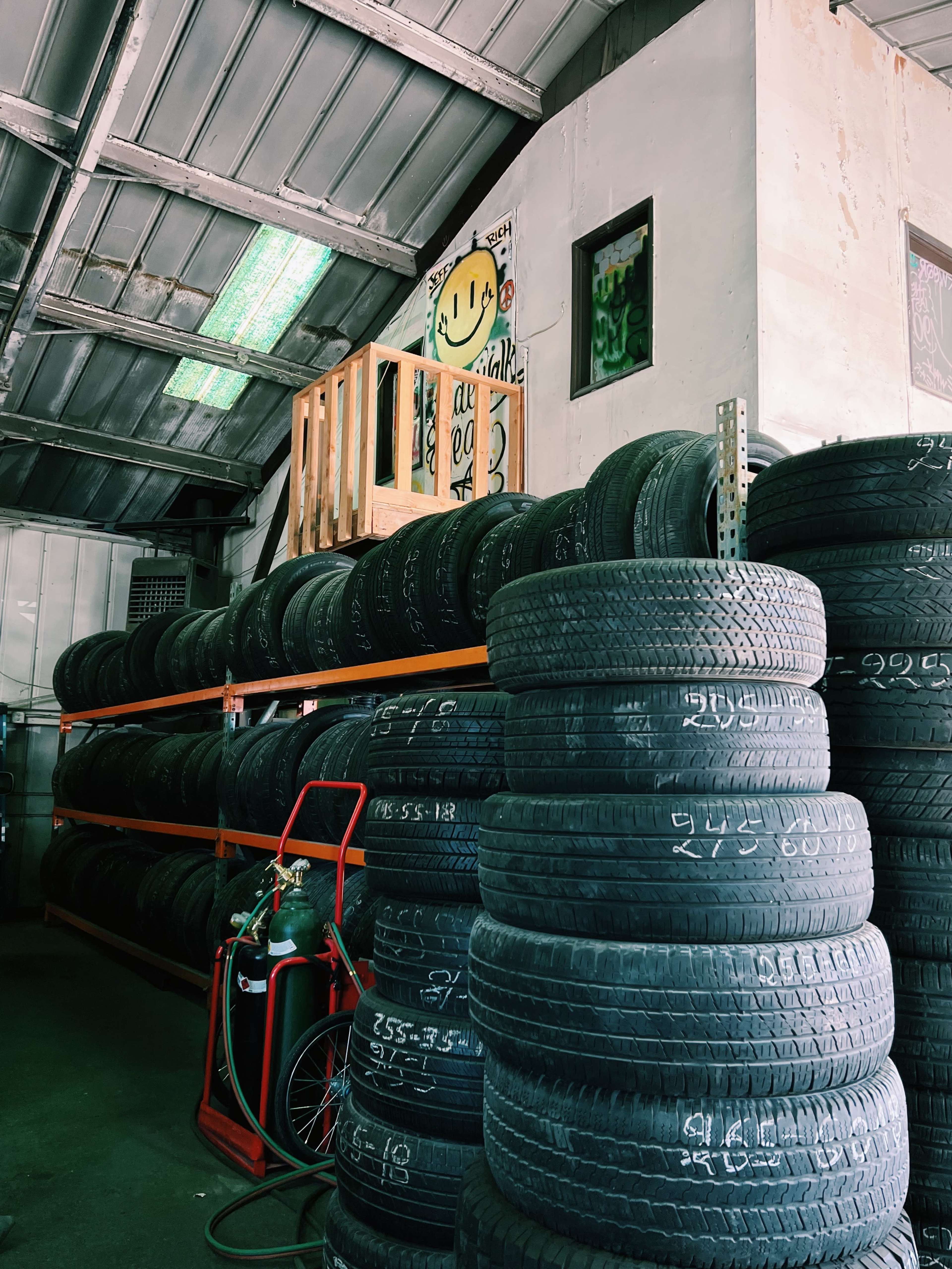 A tire storage area with stacked tires on shelves and a gas cylinder in the foreground.